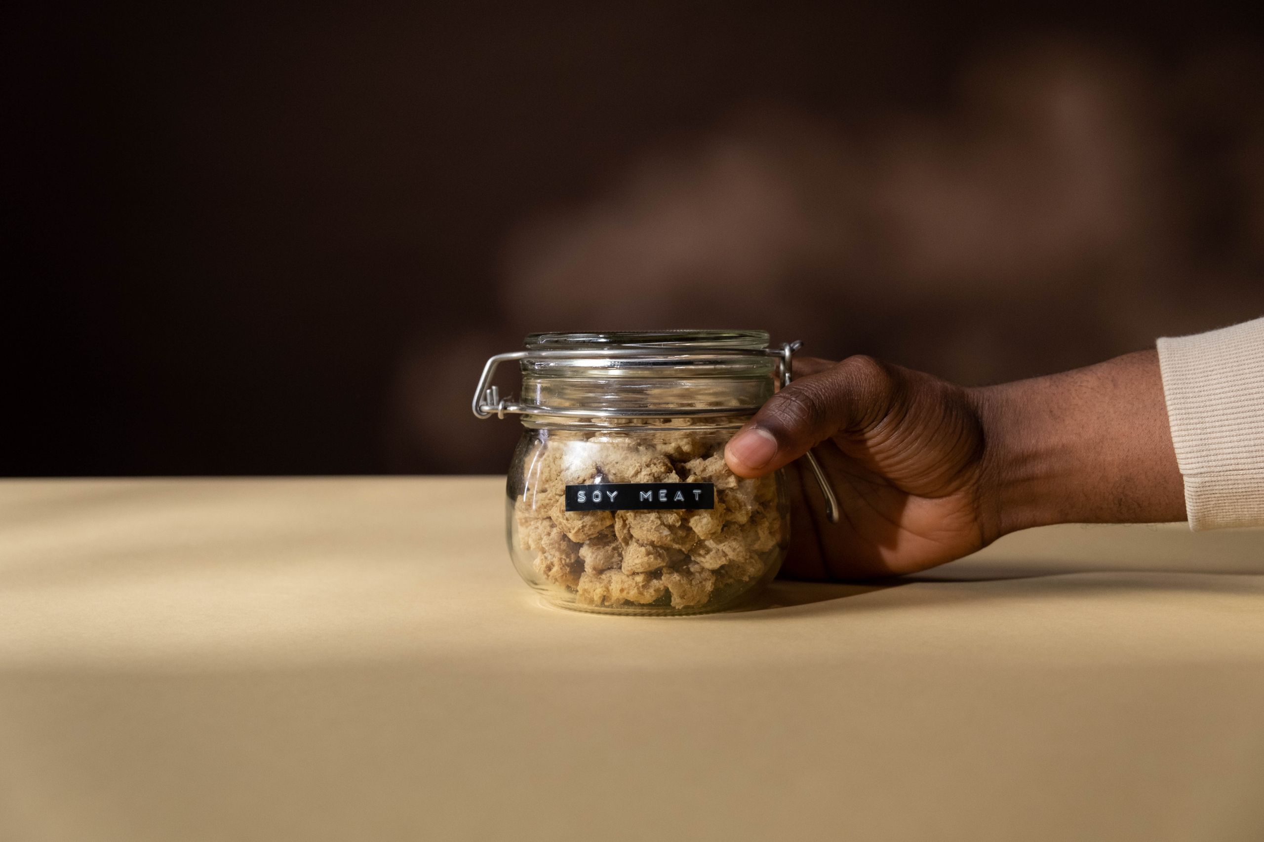 Glass jar of soy meat held in hand, emphasizing vegan nutrition and product photography.