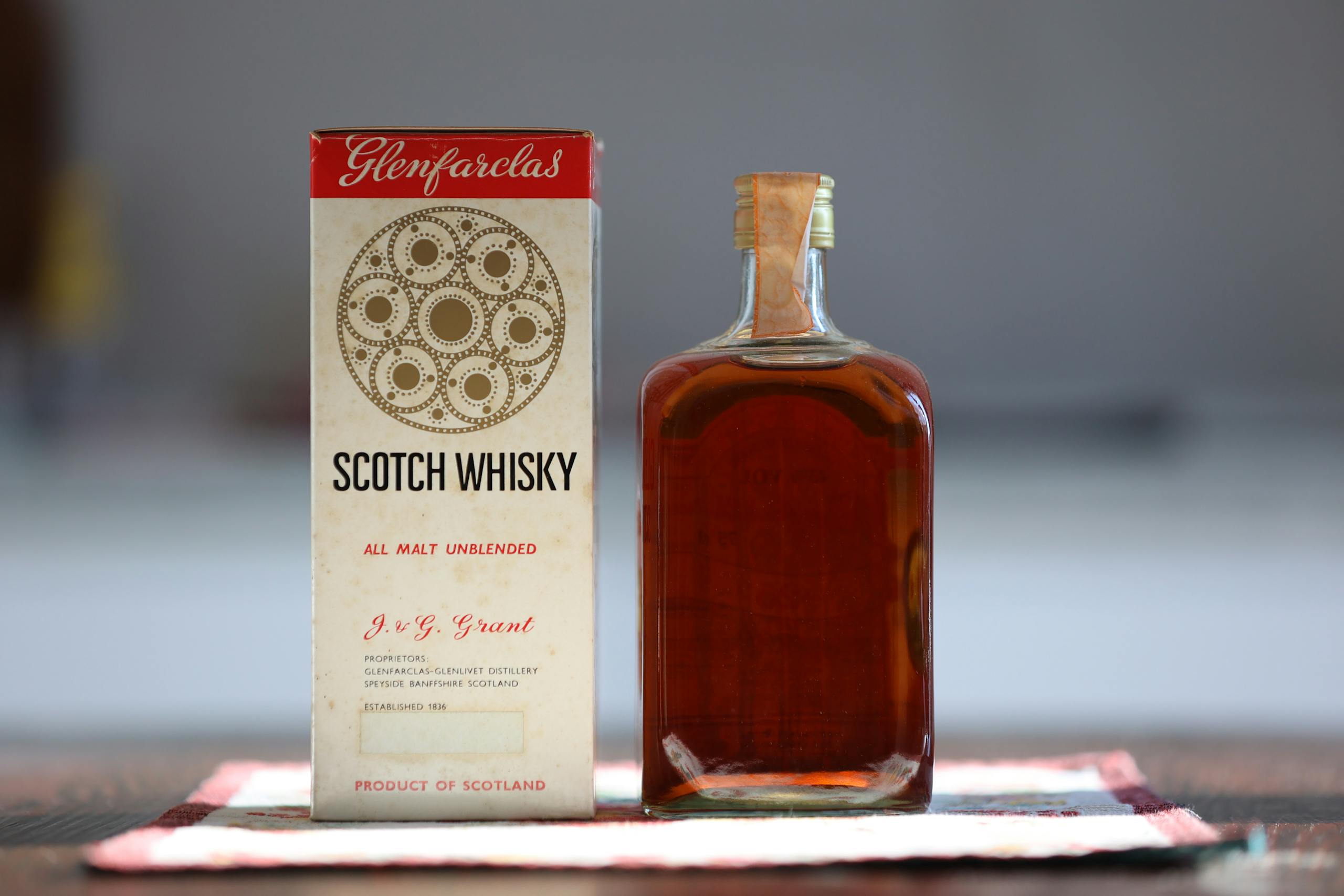 Glenfarclas Scotch whisky bottle with original packaging on a patterned cloth.
