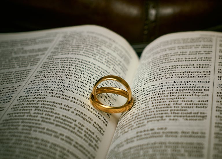 Golden wedding rings resting on an open Bible, symbolizing love and faith.