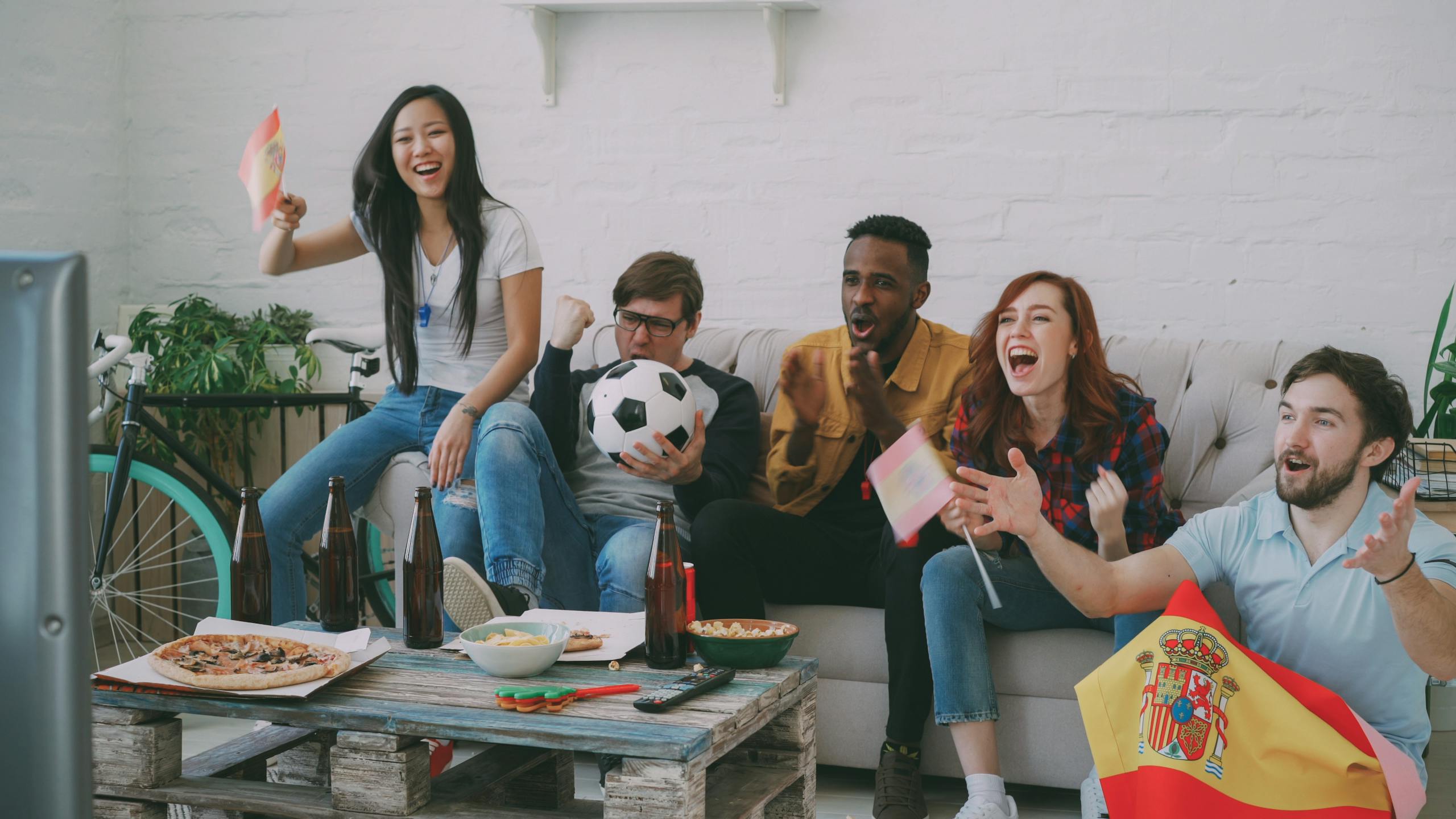 Group of friends enjoying a soccer match with snacks, flags, and cheers.