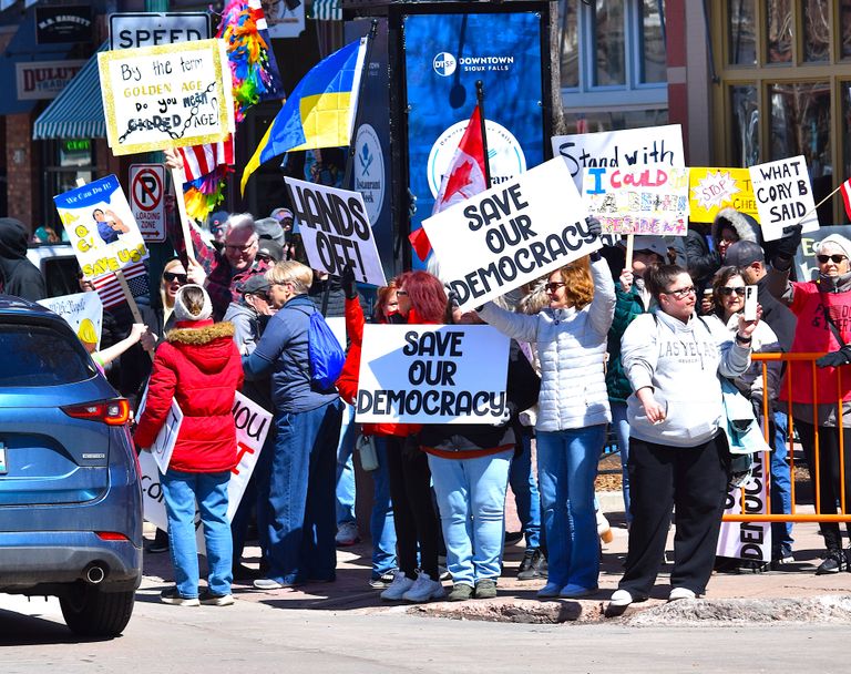 Group of people protesting for democracy in downtown Sioux Falls, holding signs for democratic rights.