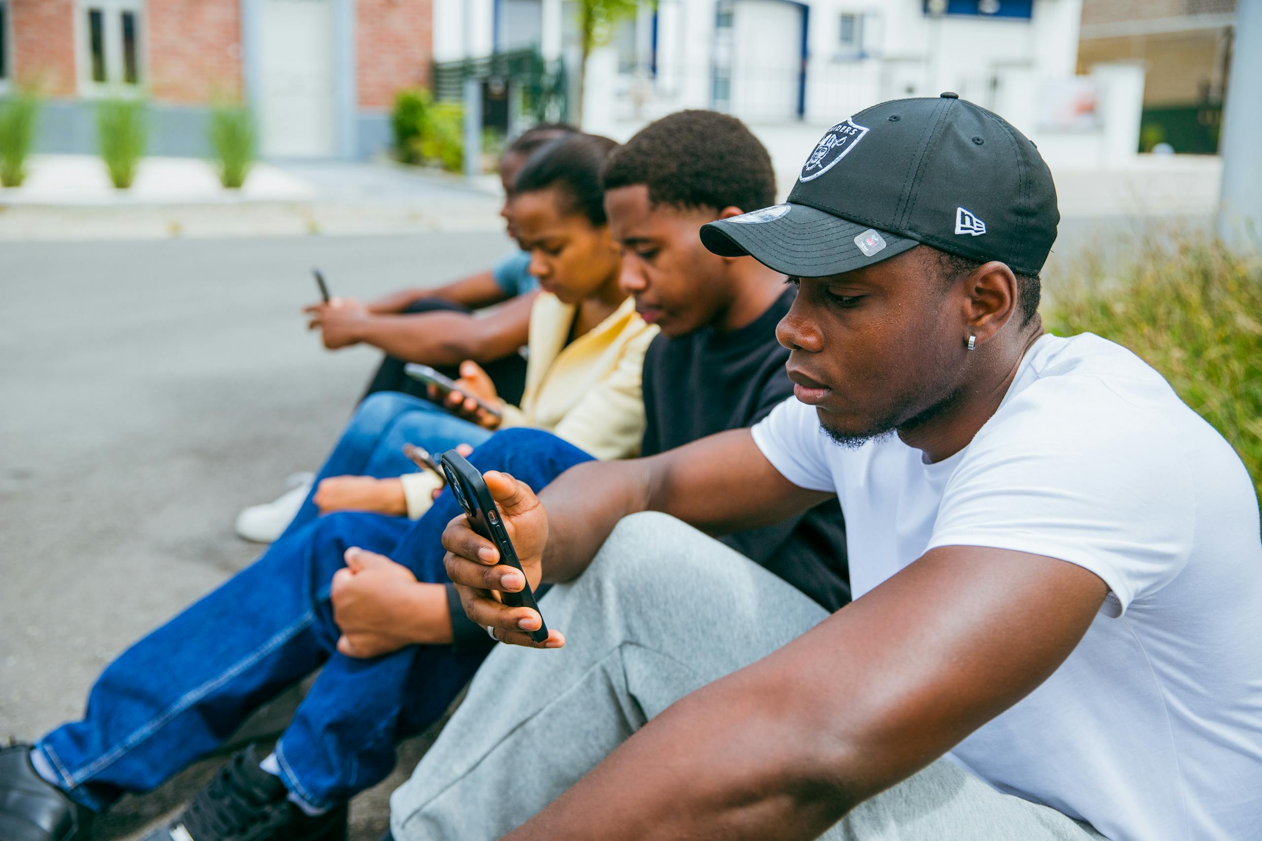 Group of young adults using smartphones seated outdoors in Brussels, capturing modern tech engagement.