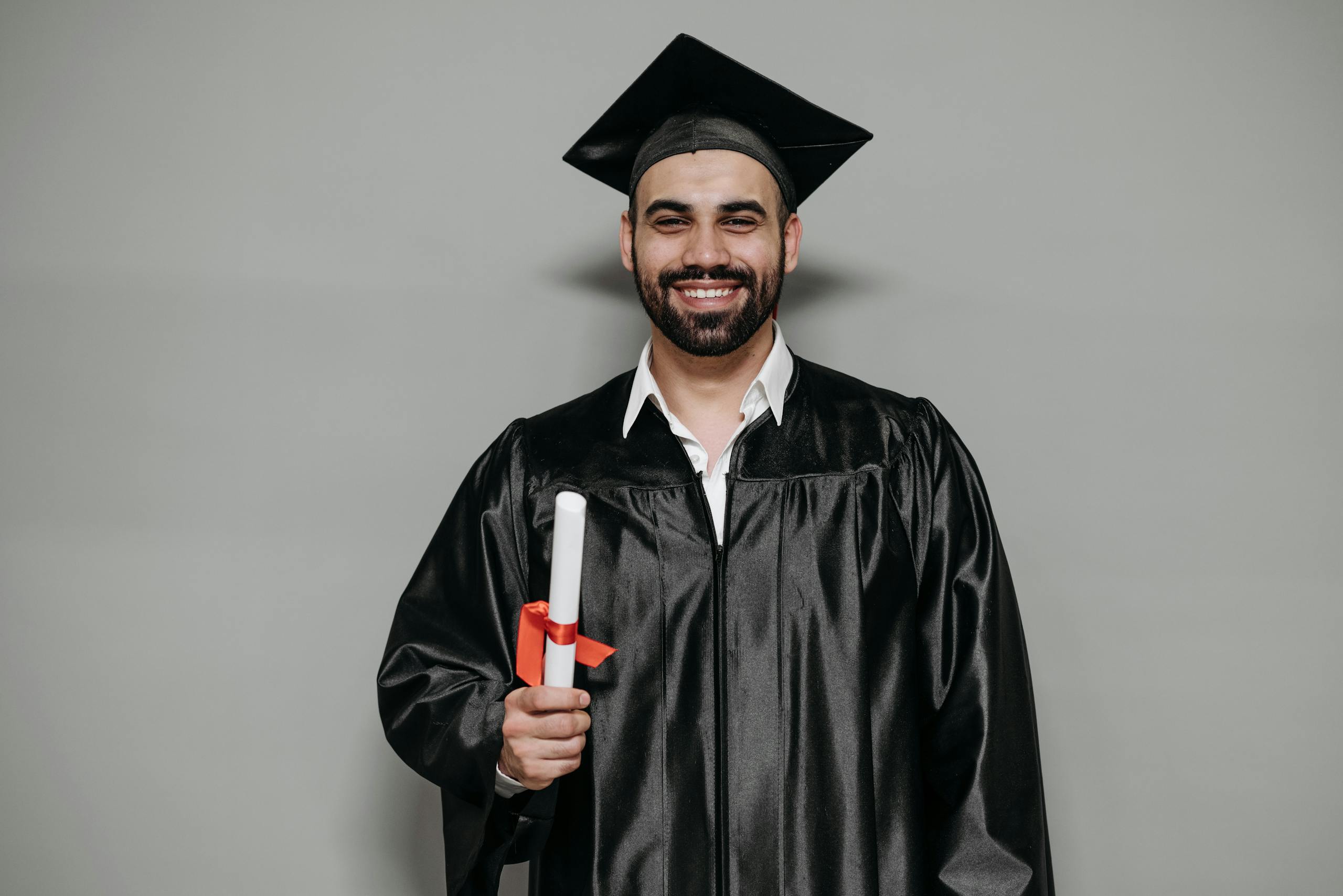 Happy bearded man in graduation attire, celebrating academic success.