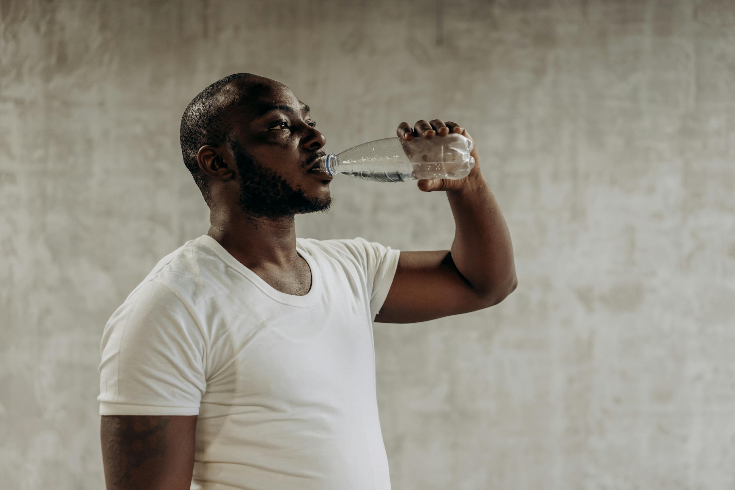 Healthy living concept: Man staying hydrated with water. Indoors, fitness focus.