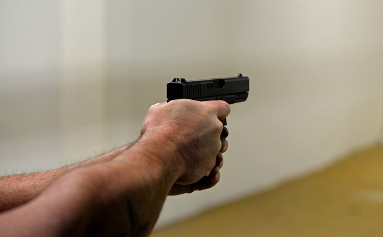 High angle of crop faceless male firing gun to target in shooting range