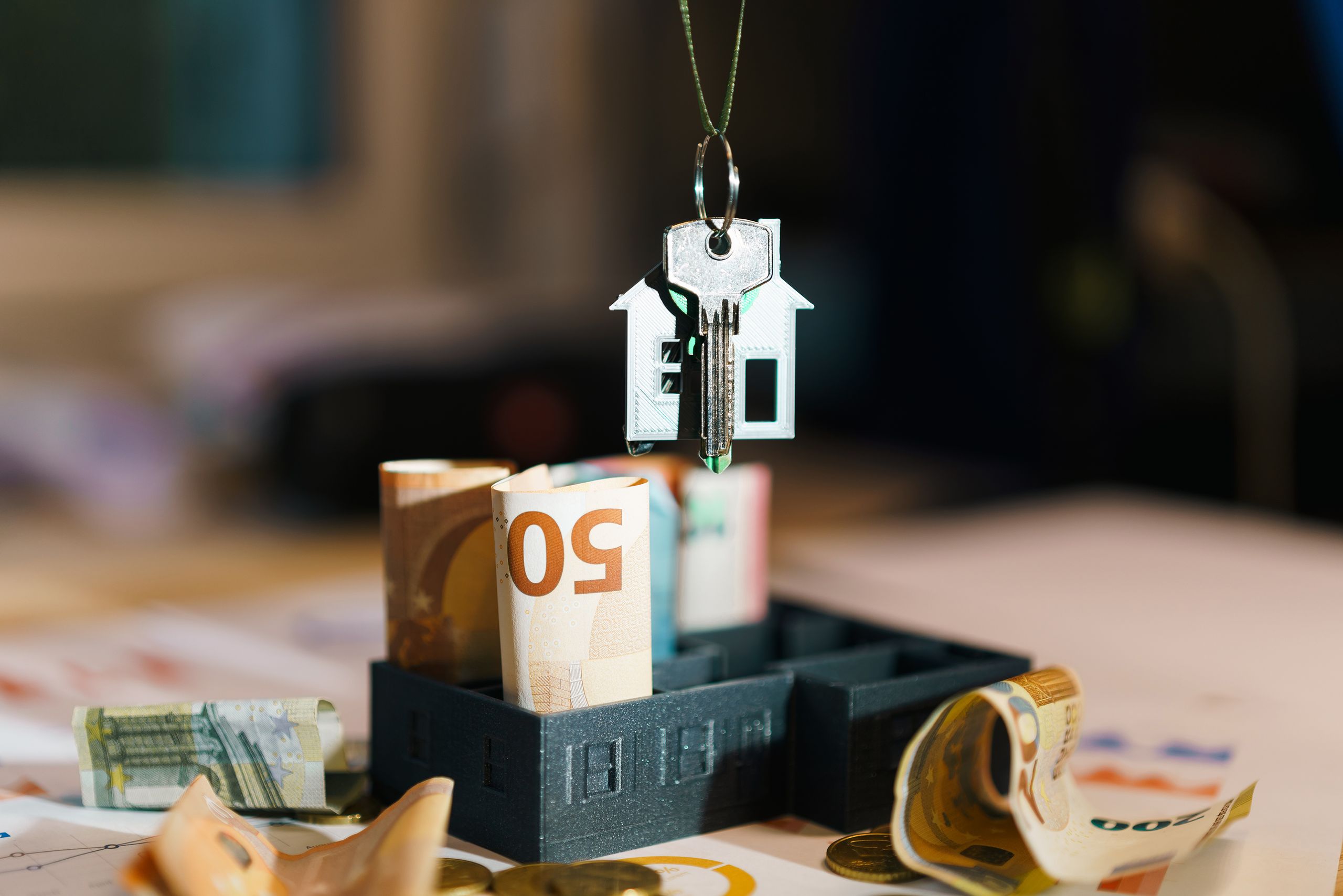House key over Euro banknotes symbolizes real estate investment and financial planning.