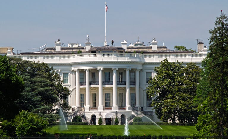 Iconic view of the White House with surrounding gardens and American flag in Washington, DC.