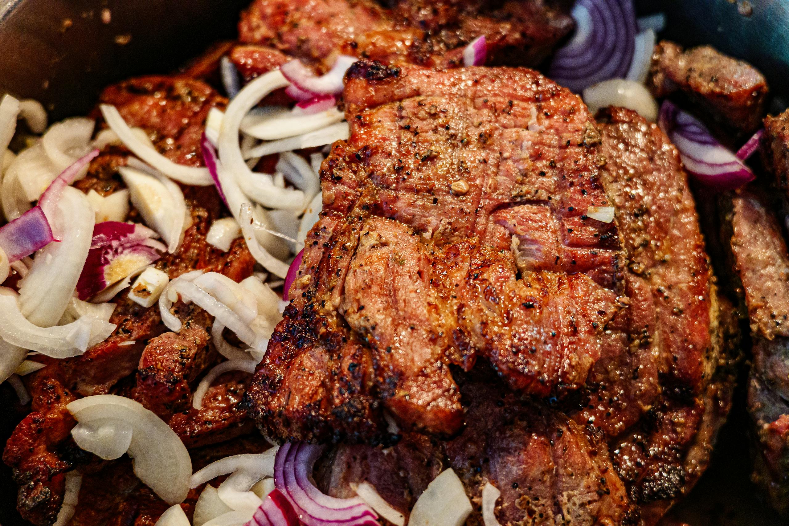 Juicy grilled steak garnished with sliced red onions, highlighting savory flavors.