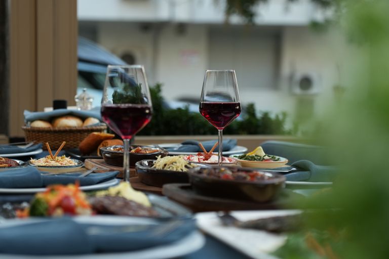 Luxurious outdoor table setting featuring red wine and a variety of gourmet dishes for a sophisticated dining experience.