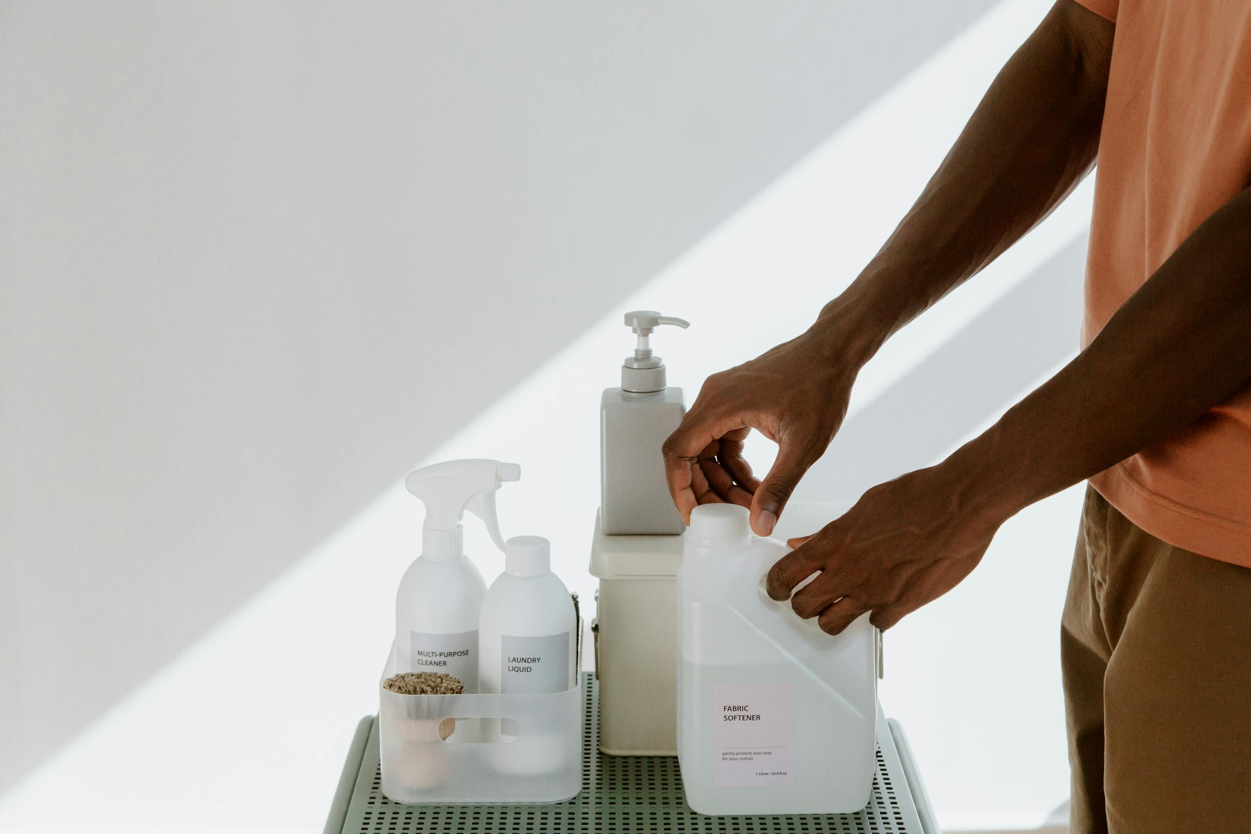 Man arranging cleaning products on a shelf, highlighting tidiness and organization.