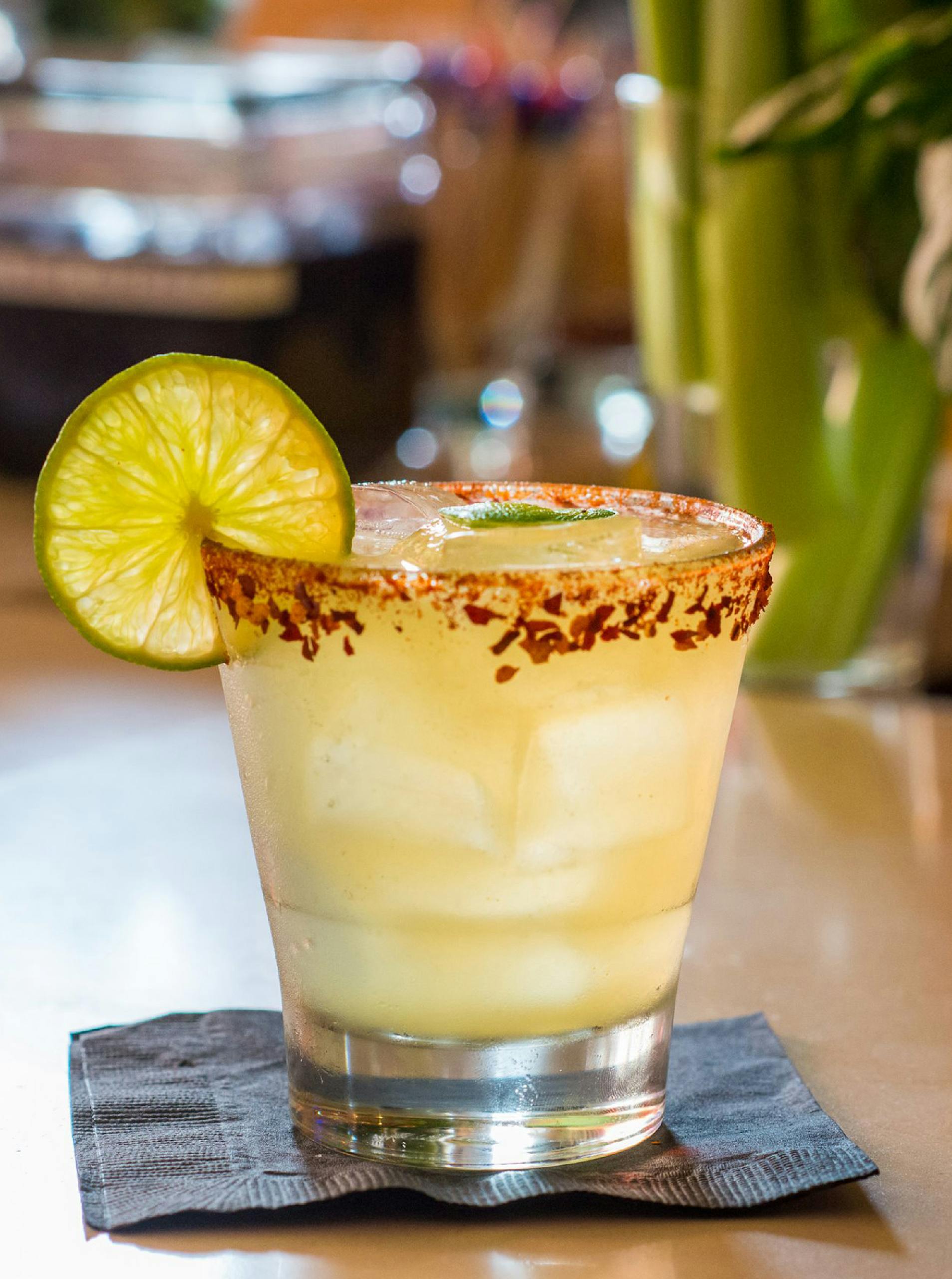 Margarita cocktail with a lime slice and chili salt rim on a napkin.