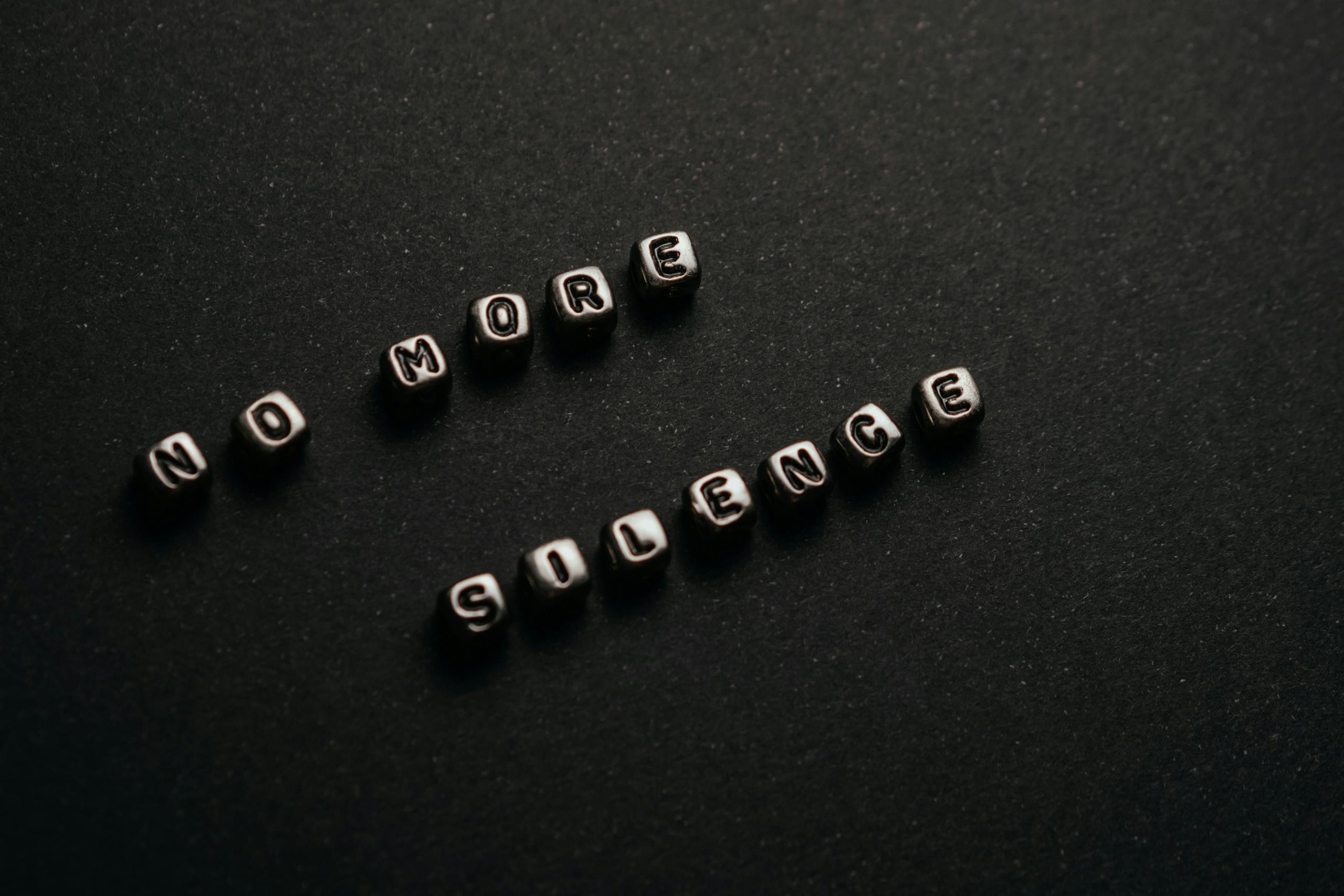 Minimalist black and white text art with message 'No More Silence' on a dark background.