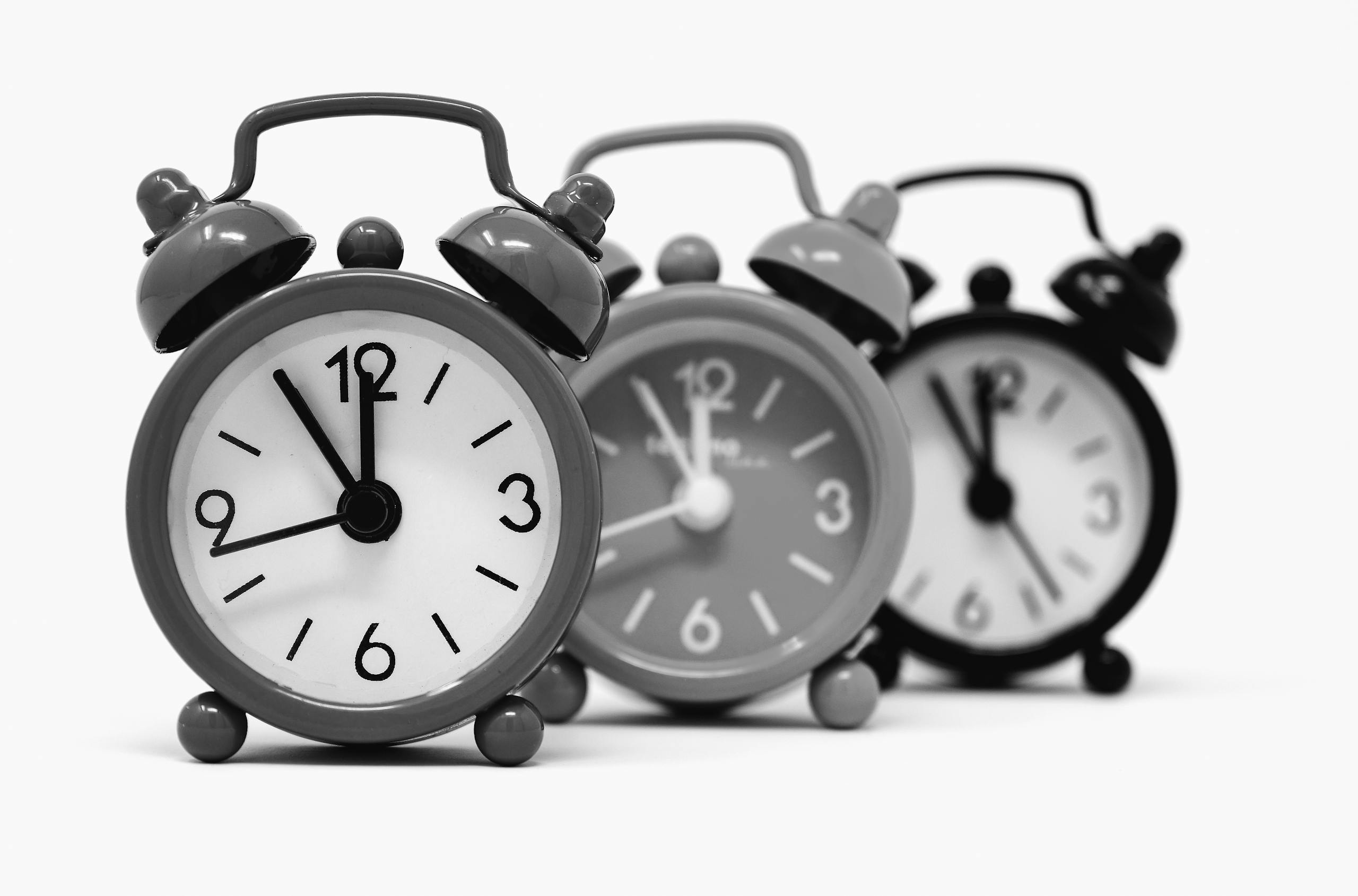 Monochrome image of three vintage alarm clocks highlighting the passage of time.