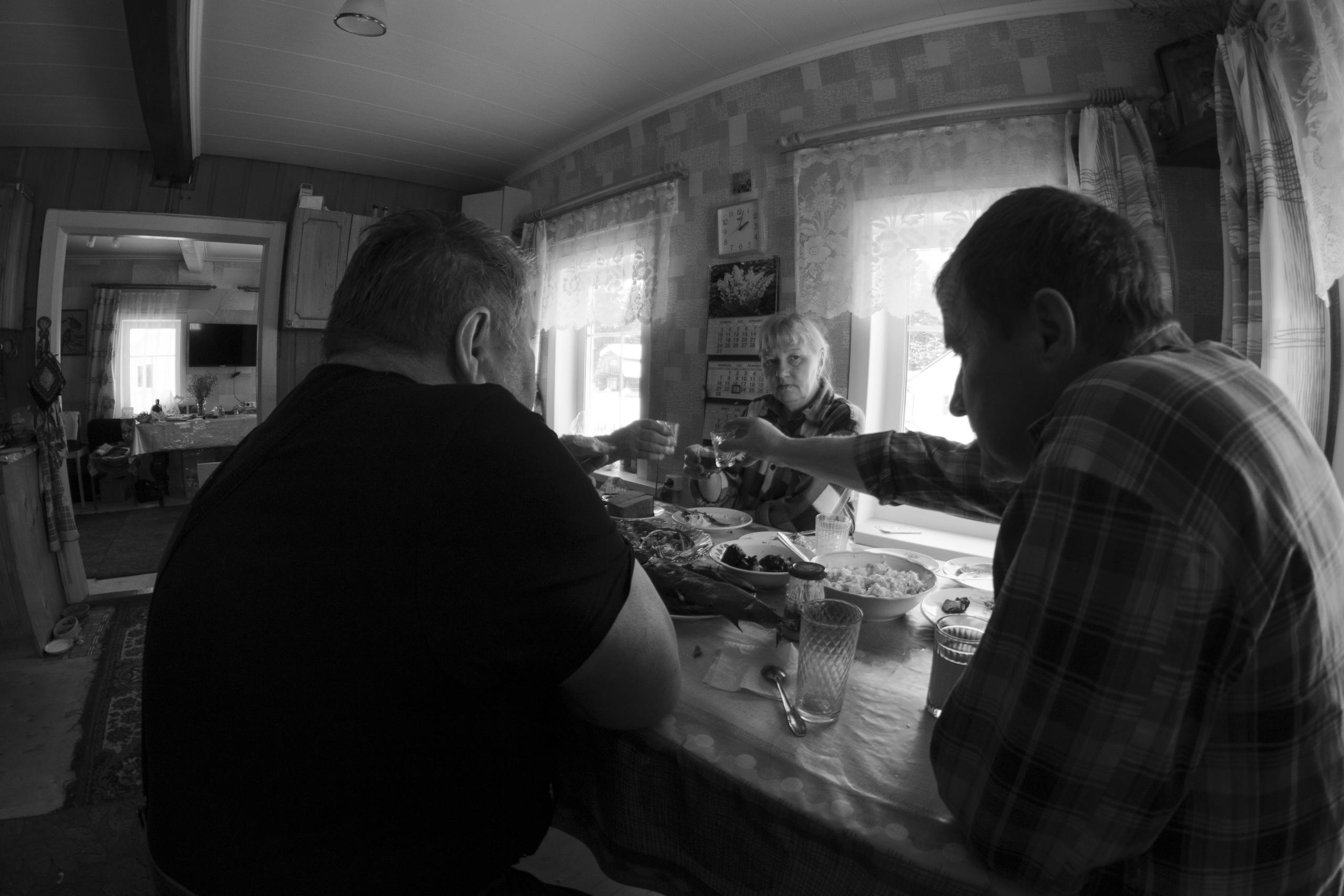 Monochrome scene of family toasting indoors around a table, evoking warmth and togetherness.
