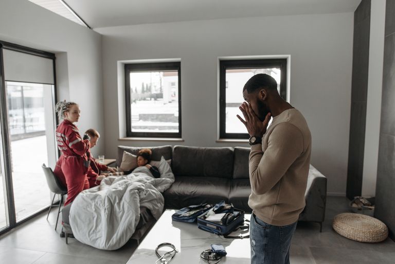 Paramedics provide emergency care to a patient in a modern home setting. Concerned family present.