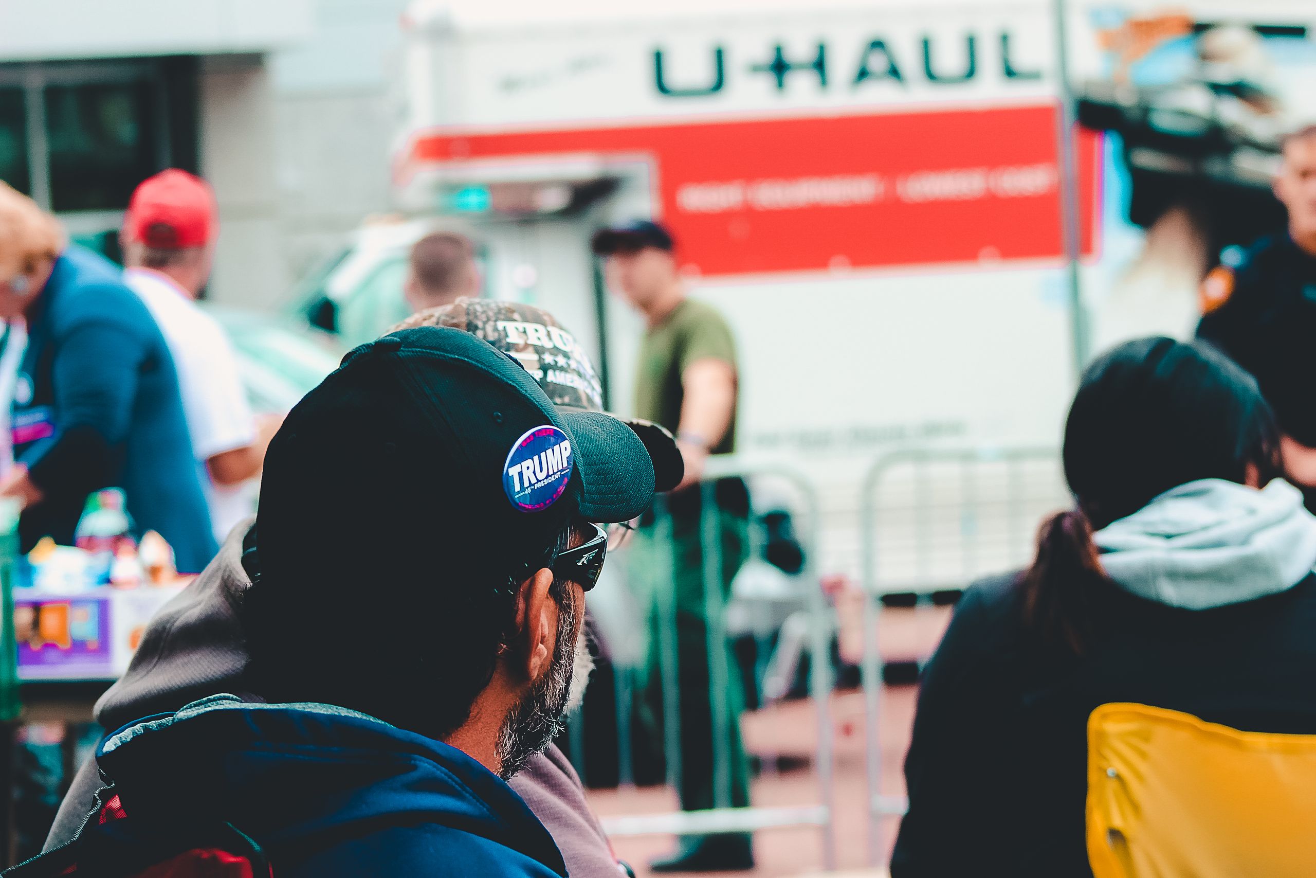 Participants at a political rally in Wheeling, WV wearing campaign merchandise with a U-Haul in the background.