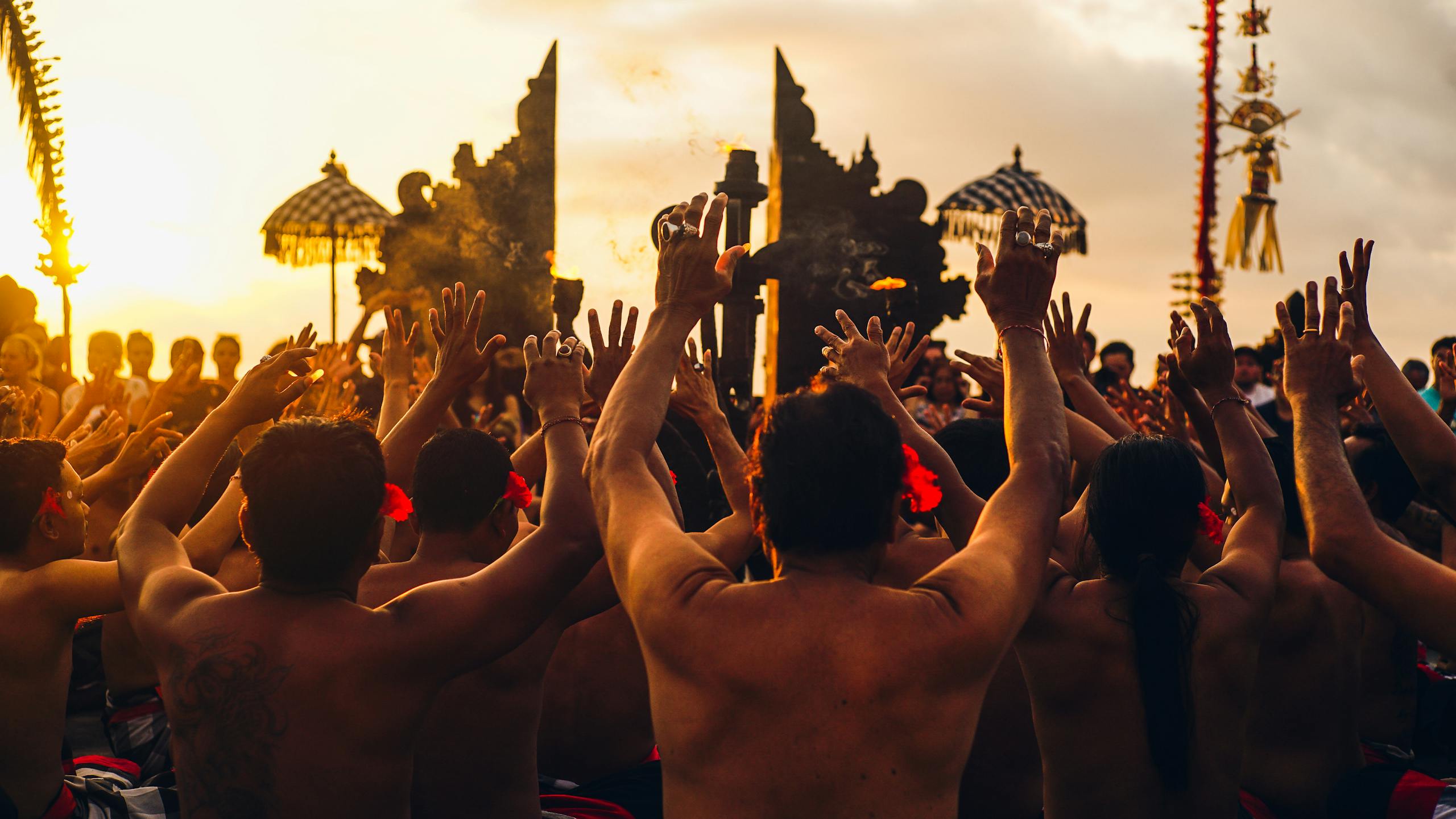 Participants embrace Balinese culture during a Kecak dance at sunset in Bali, Indonesia.
