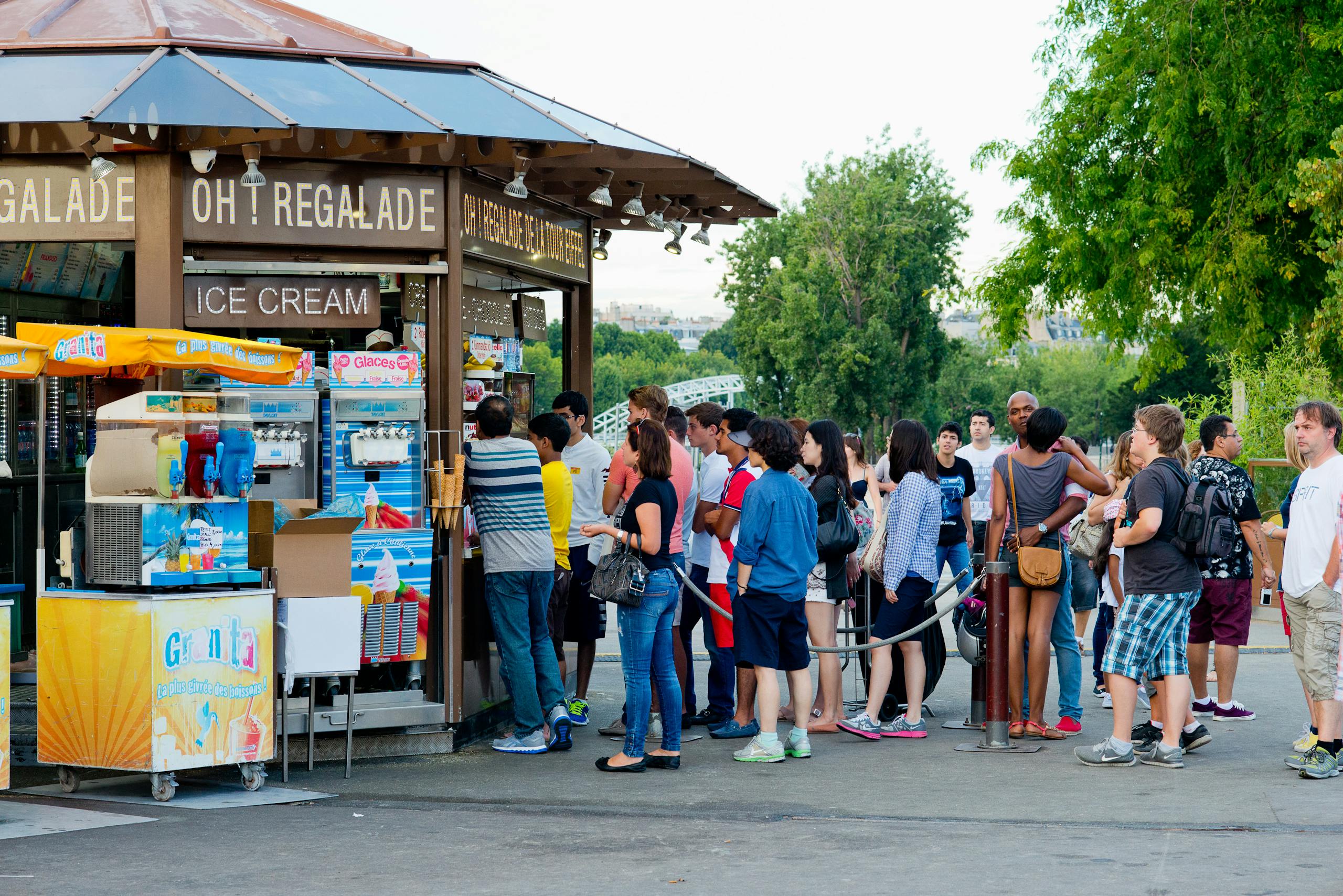 People queue for ice cream at a park stand in Paris, France, during a warm day.