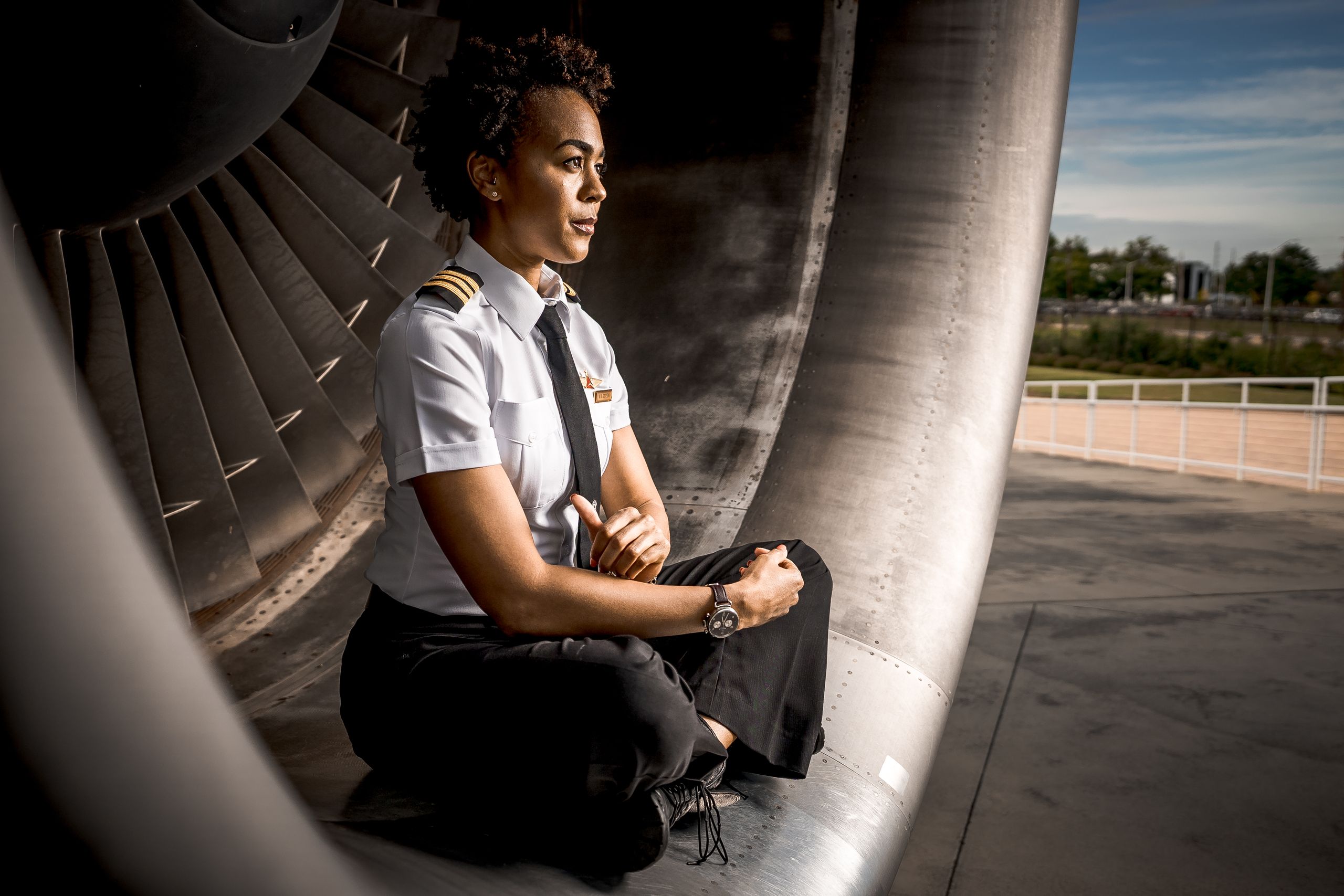 Portrait of a pilot sitting inside an aircraft engine, exuding confidence and professionalism.