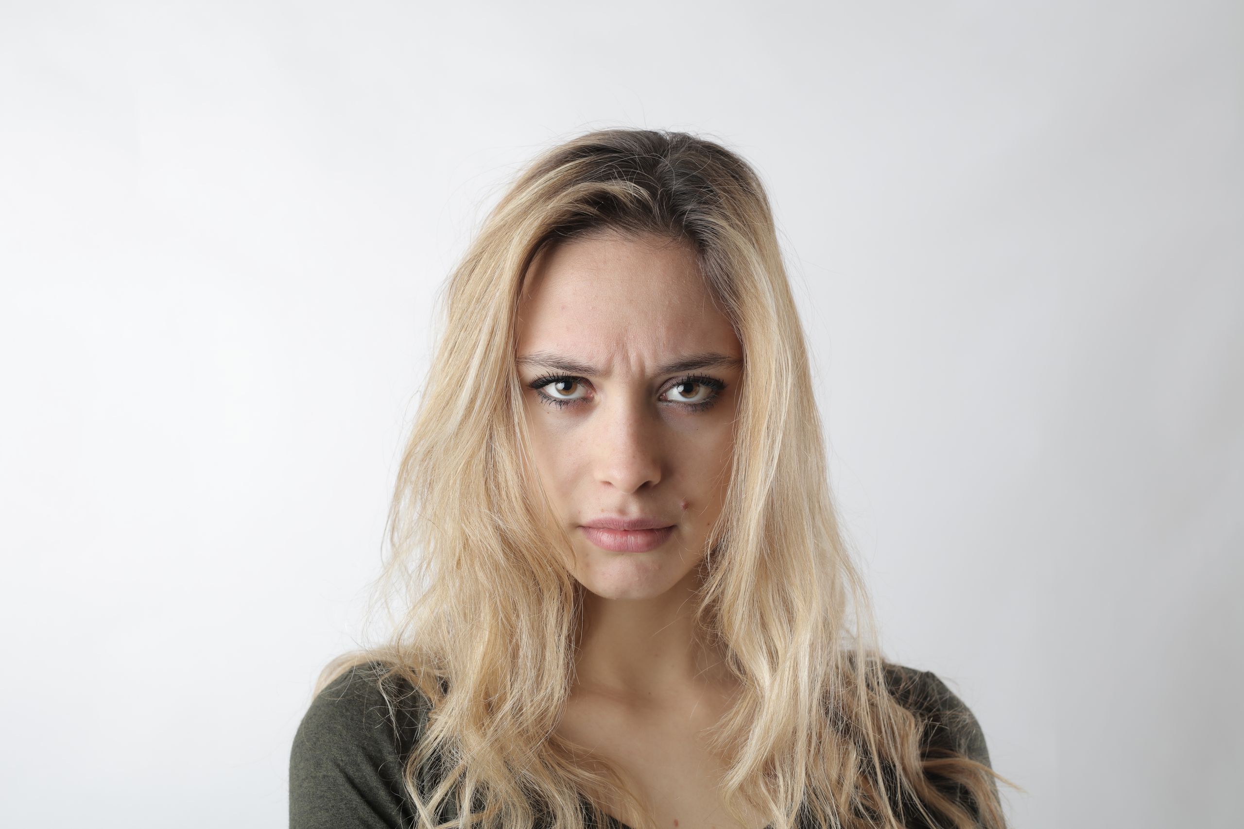 Portrait of a woman with blonde hair displaying a focused expression against a white background.