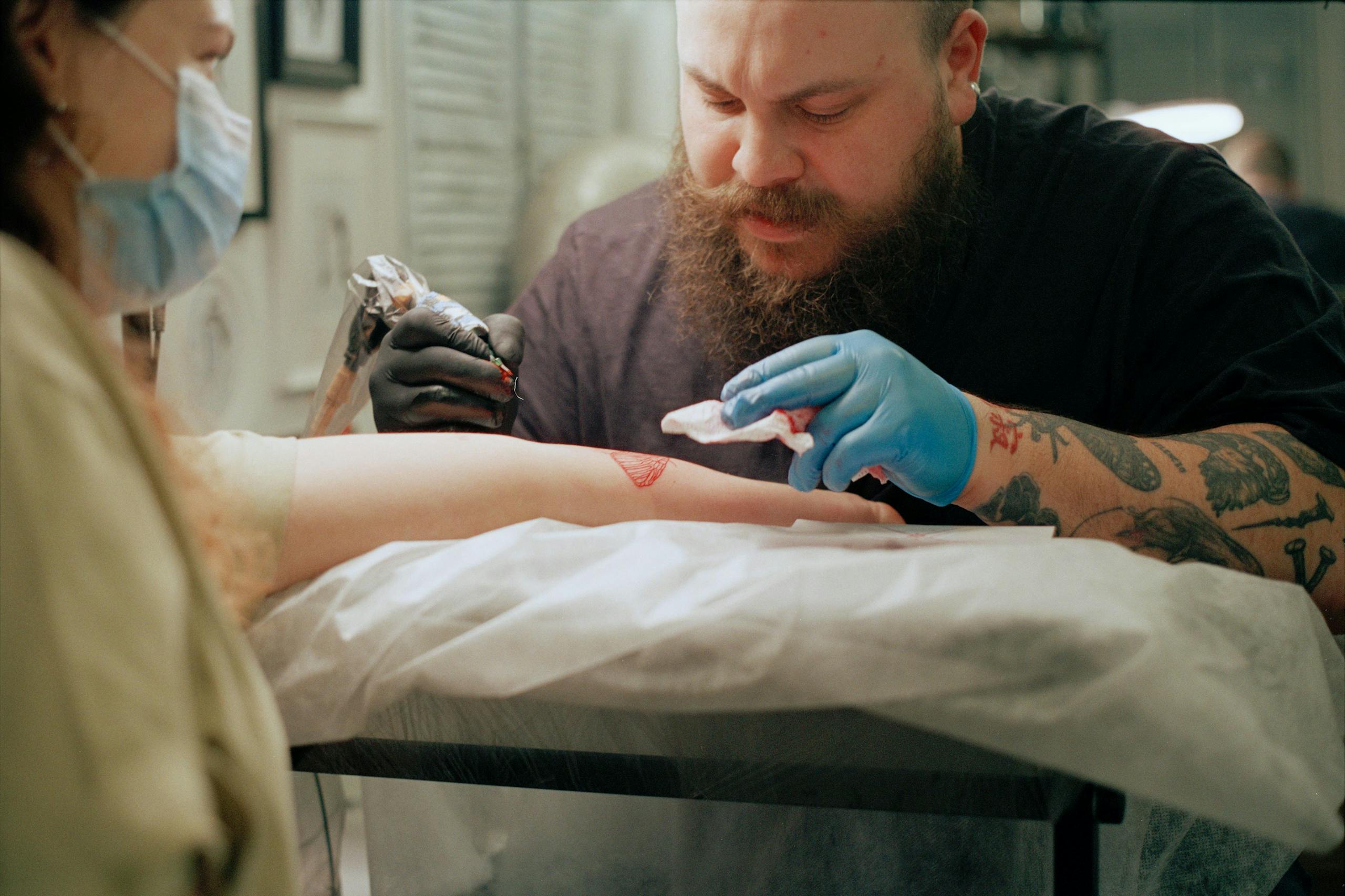 Professional tattoo artist creating arm tattoos in a studio setting. Capturing the art process.