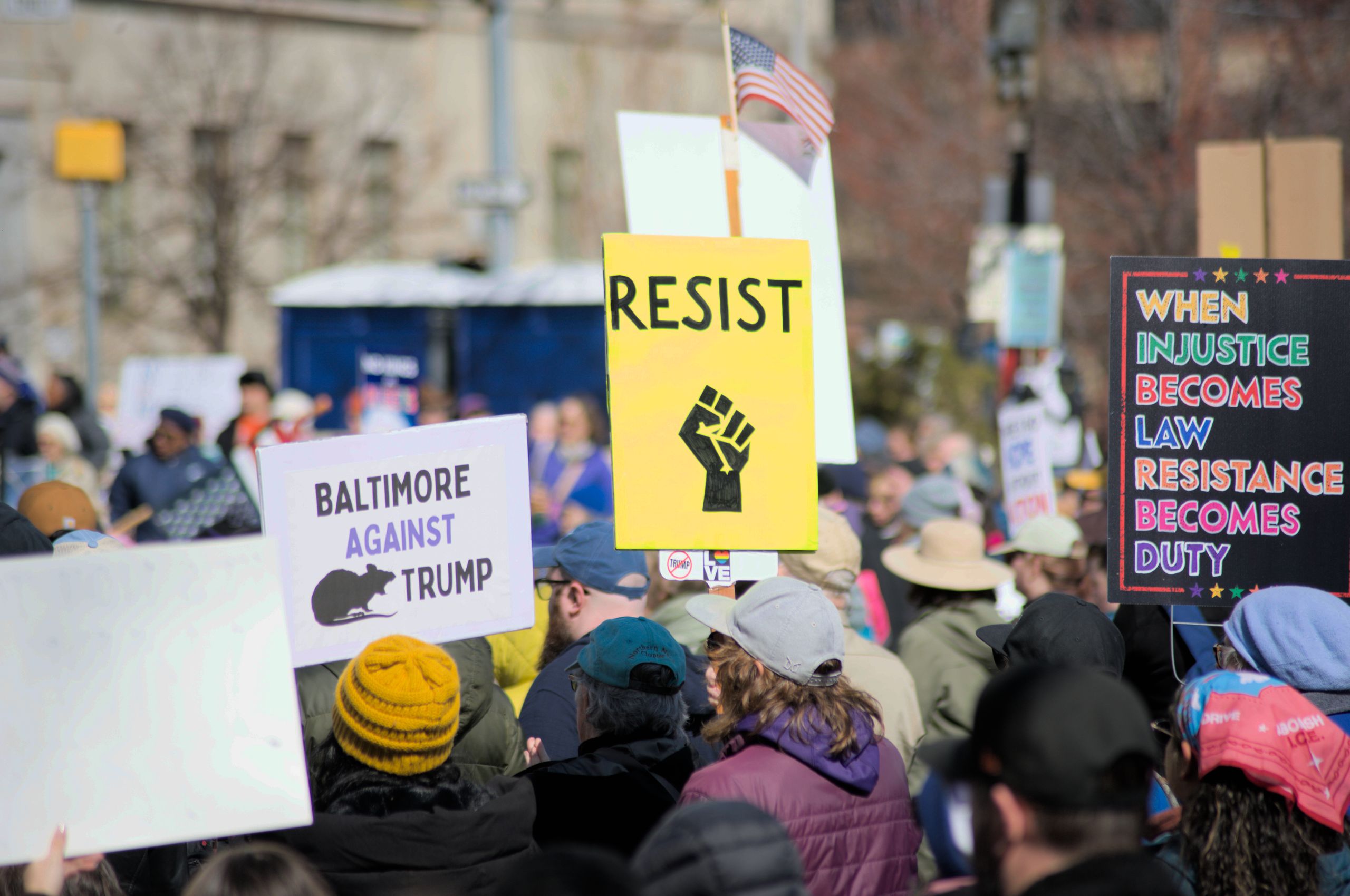 Protesters in Baltimore hold signs advocating resistance and social justice. Location: Baltimore, Maryland.