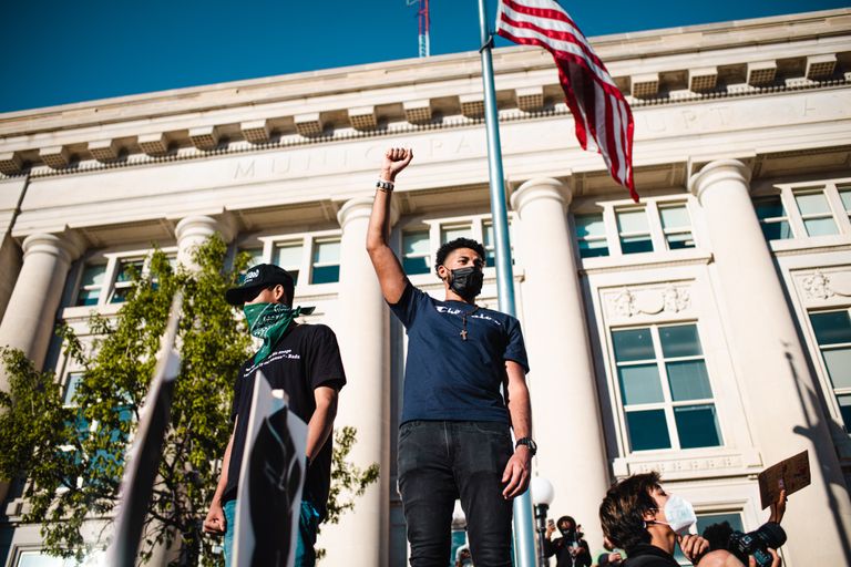 Protesters in Des Moines advocate for freedom with raised fists and American flag backdrop.