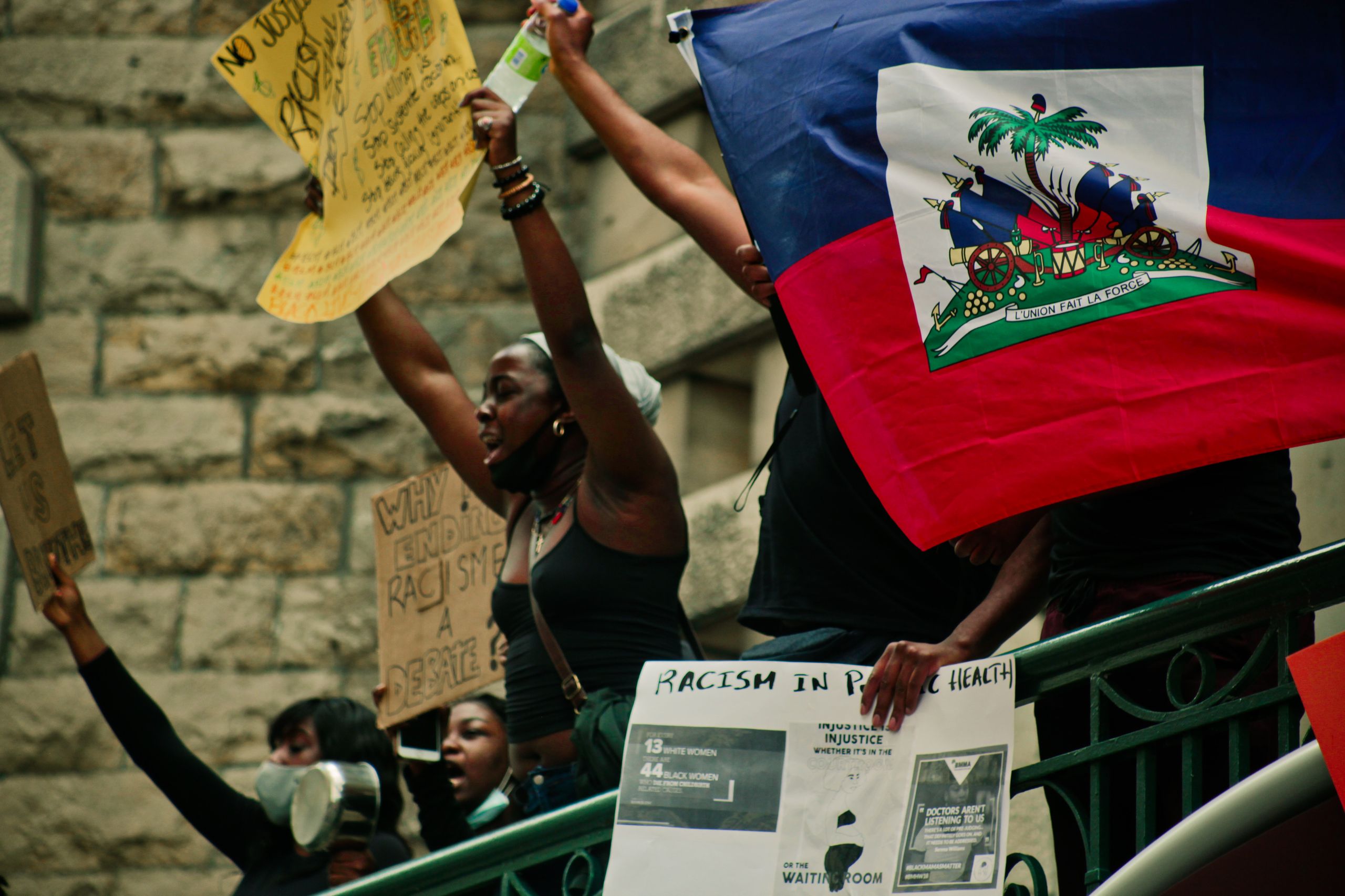 Protesters in Montreal holding Haitian flag and signs advocating for racial justice.