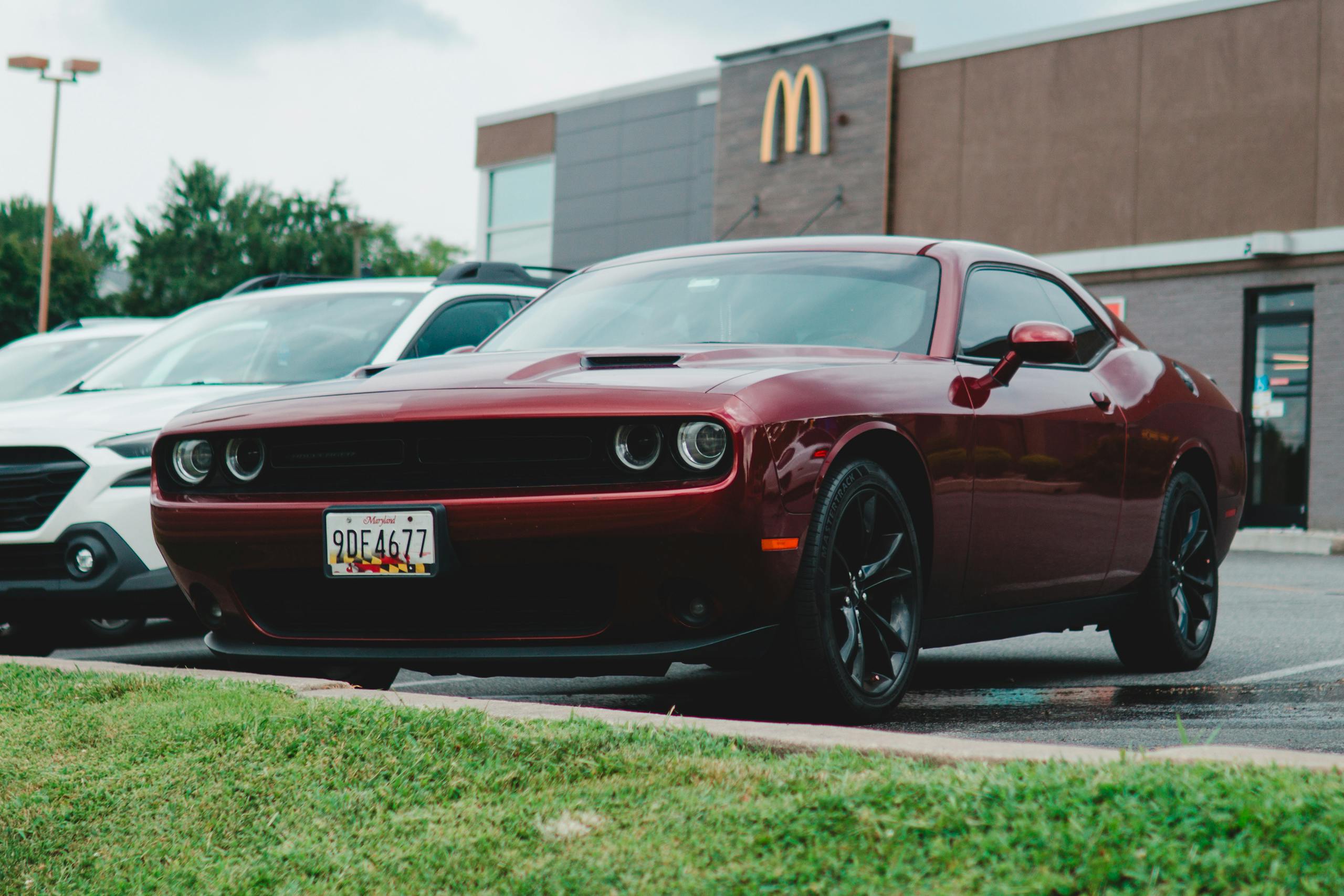 A red Dodge Challenger parked in a McDonald's lot, showcasing its sleek design.