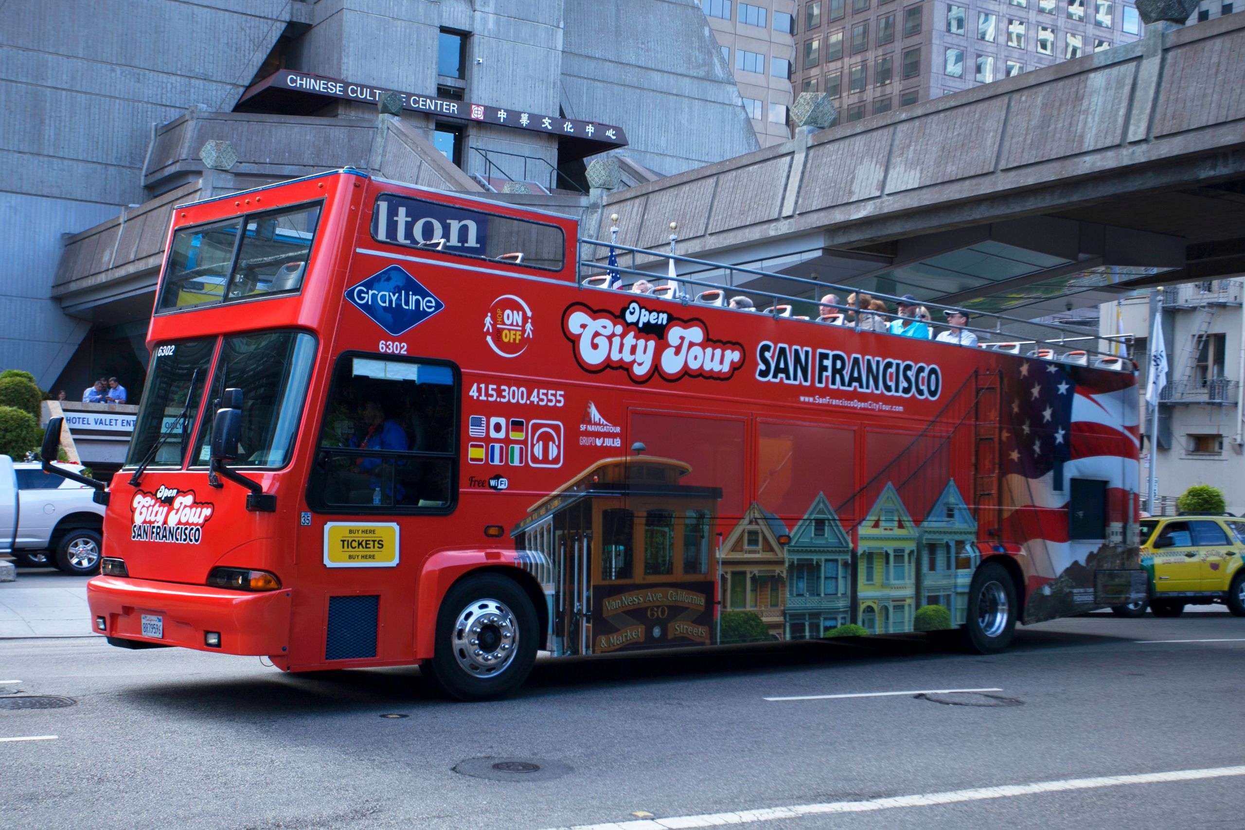 Red double decker bus on a city tour of San Francisco, featuring iconic landmarks.