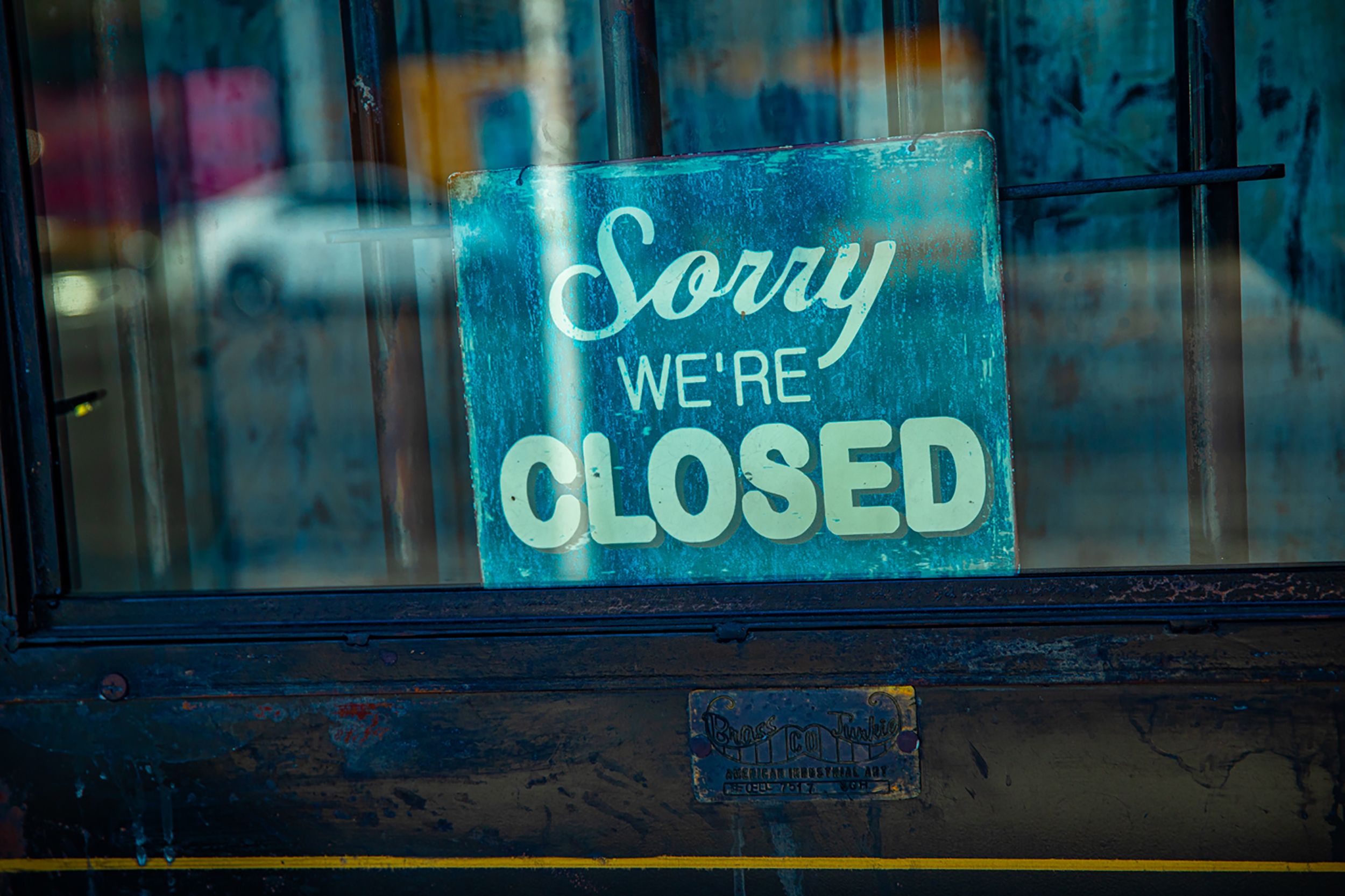 Retro 'Sorry We're Closed' sign displayed on a rustic glass door, depicting temporary closure.