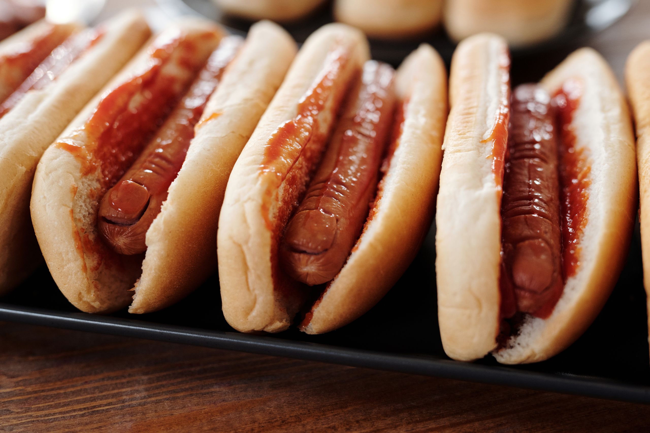 Row of hot dogs topped with ketchup, showcasing a savory snack in a close-up view.
