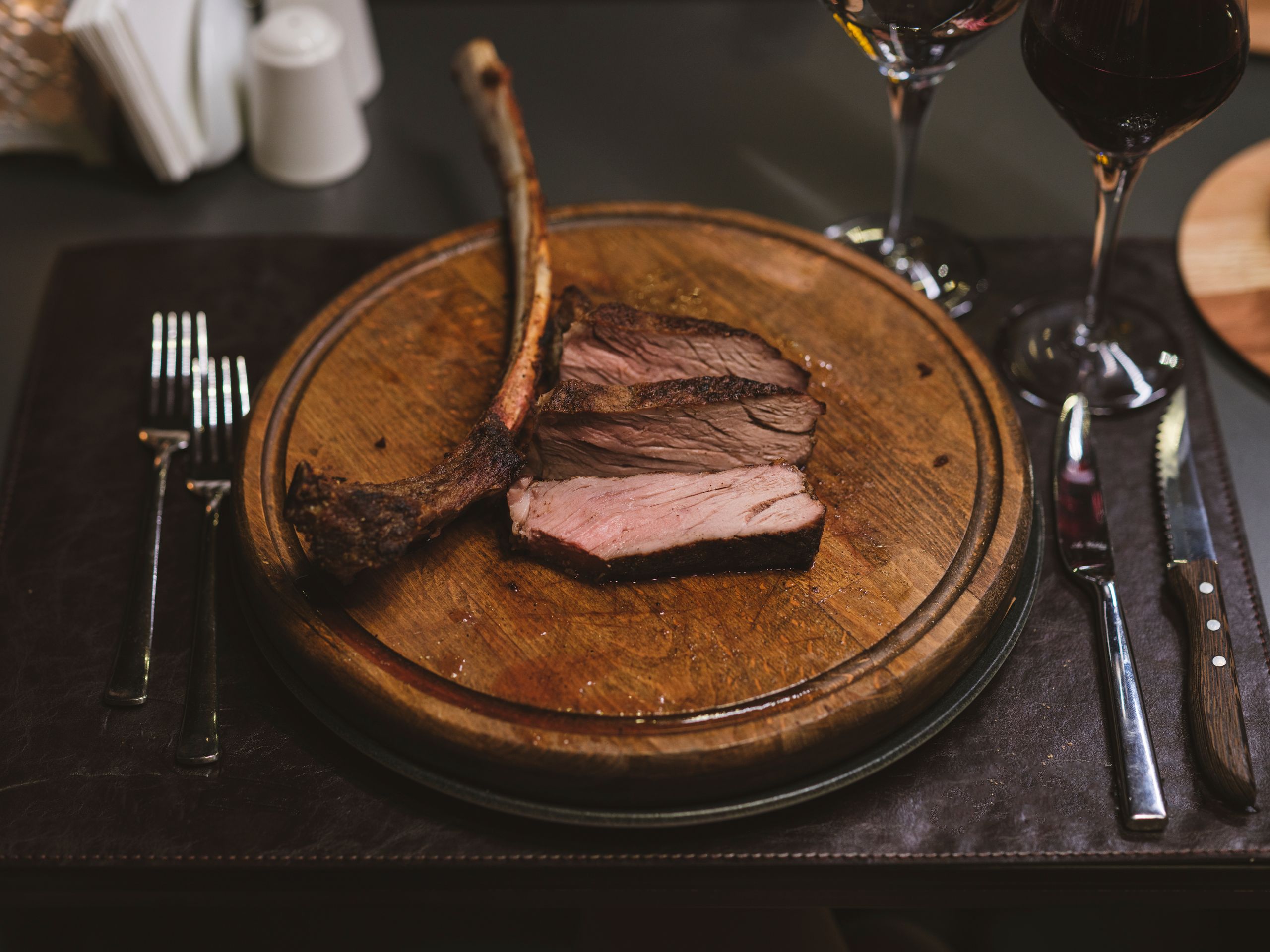 Savor a delectable beef steak served on a rustic wooden board, paired with red wine.