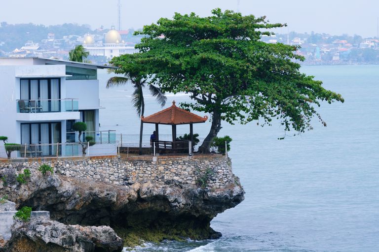 Scenic view of a house and gazebo on a cliff overlooking the ocean, providing a peaceful escape.