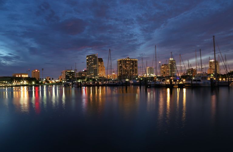 Scenic view of St. Petersburg, FL marina at dusk, featuring skyline and reflections in water.