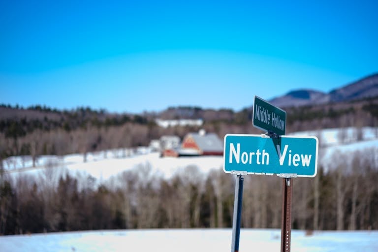 Scenic winter landscape featuring a road sign and rural farmland in Vermont.