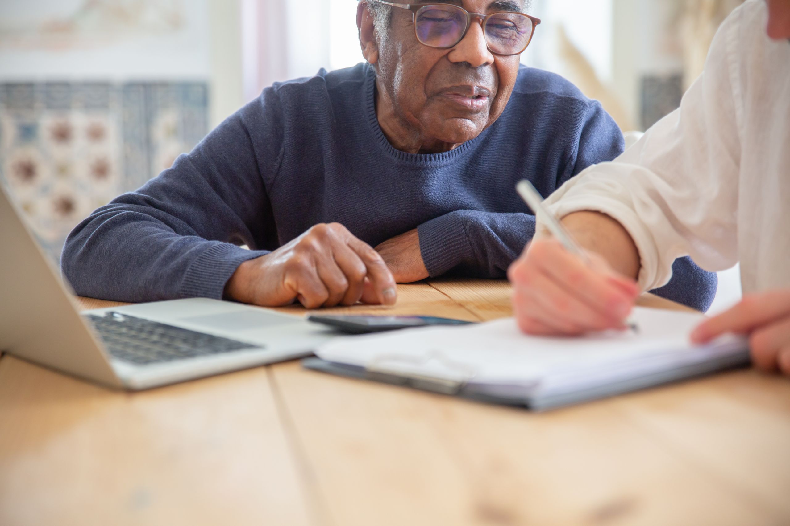 Senior African American man receiving assistance with paperwork at home.