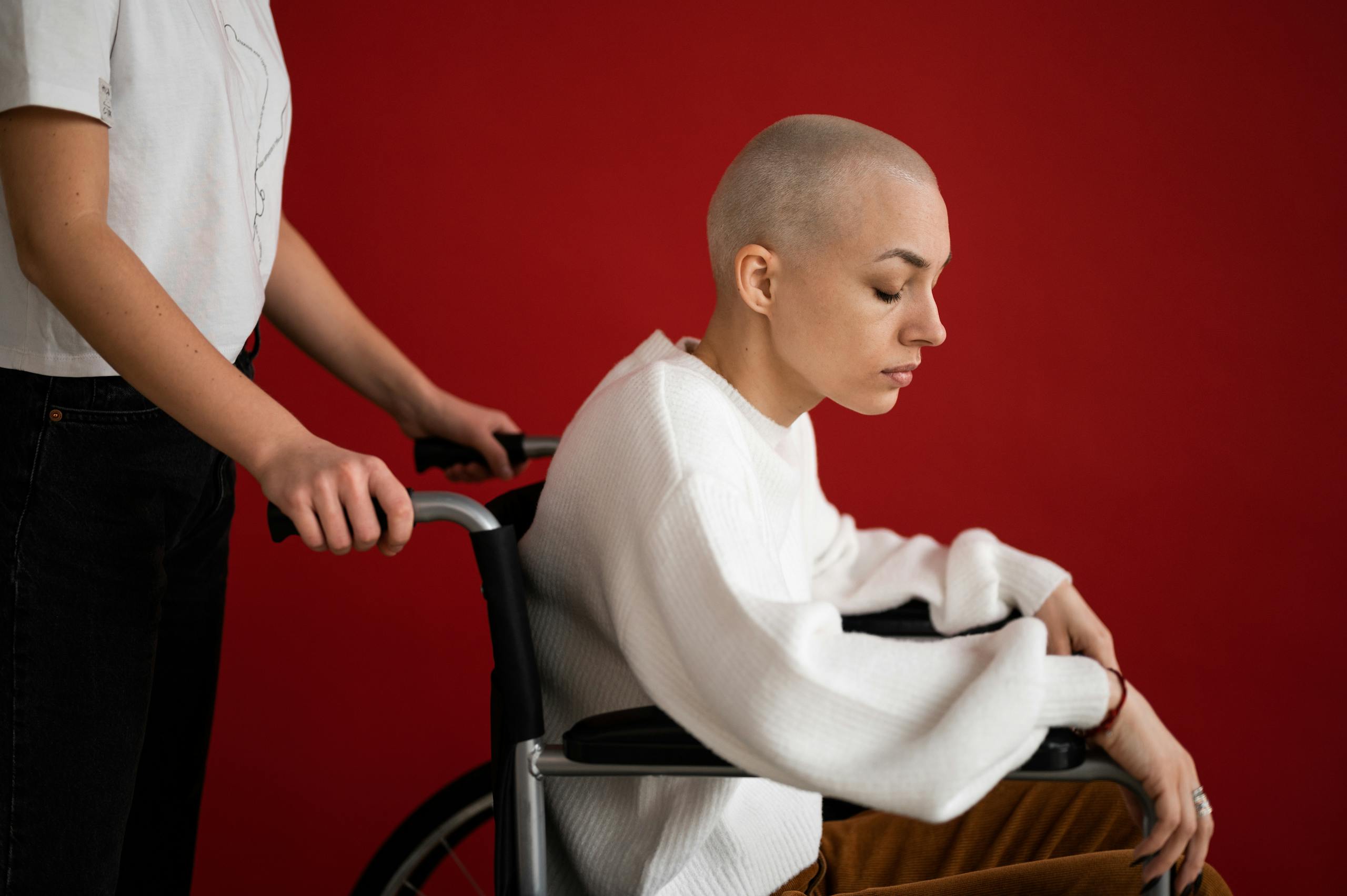 Side view of crop unrecognizable partner pushing wheelchair with handicapped woman with closed eyes during cancer rehabilitation process