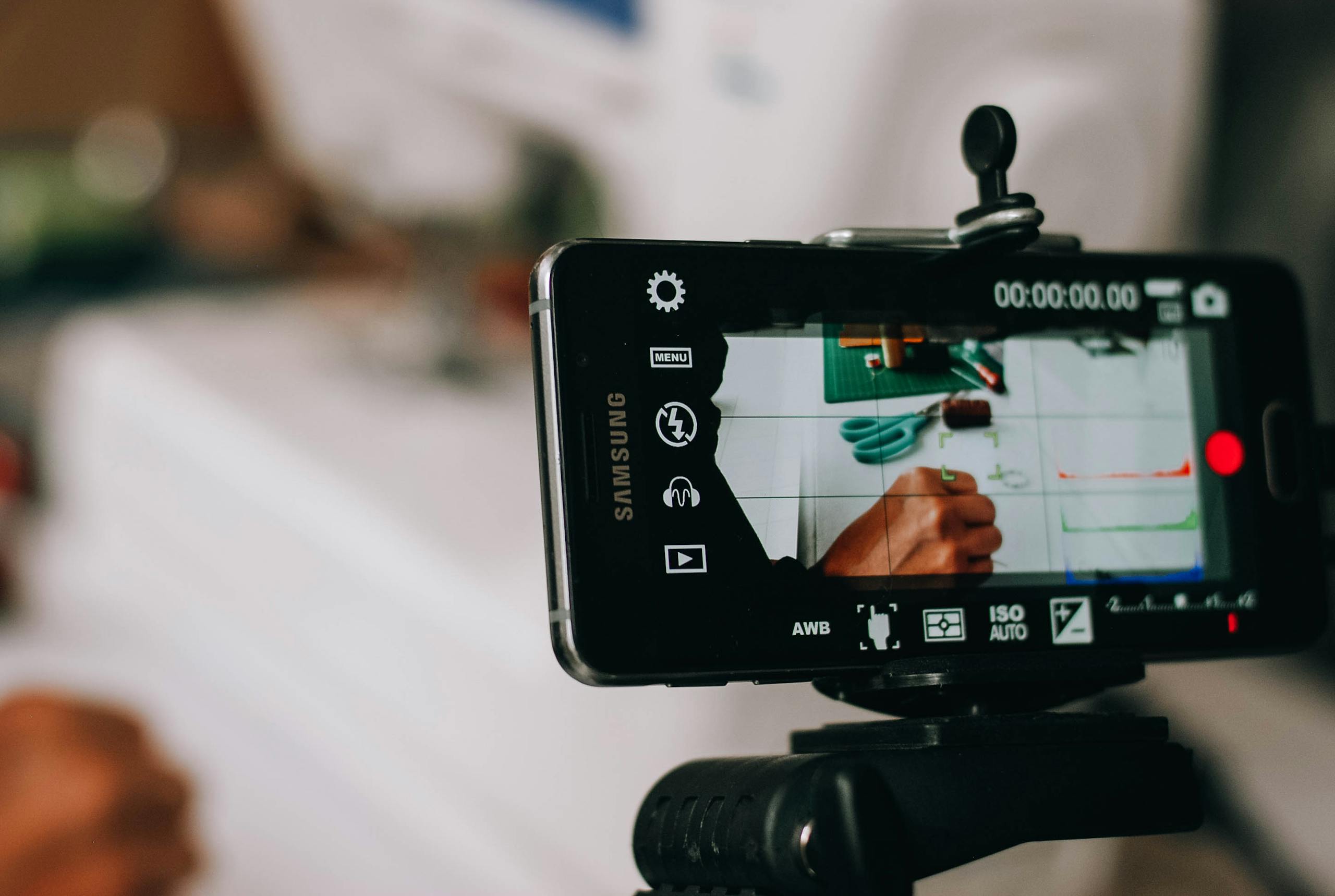 Smartphone on tripod capturing person writing on paper, showing content creation process.