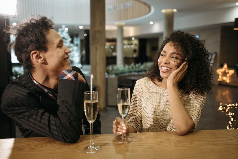 Smiling couple enjoying champagne at a stylish indoor bar setting.