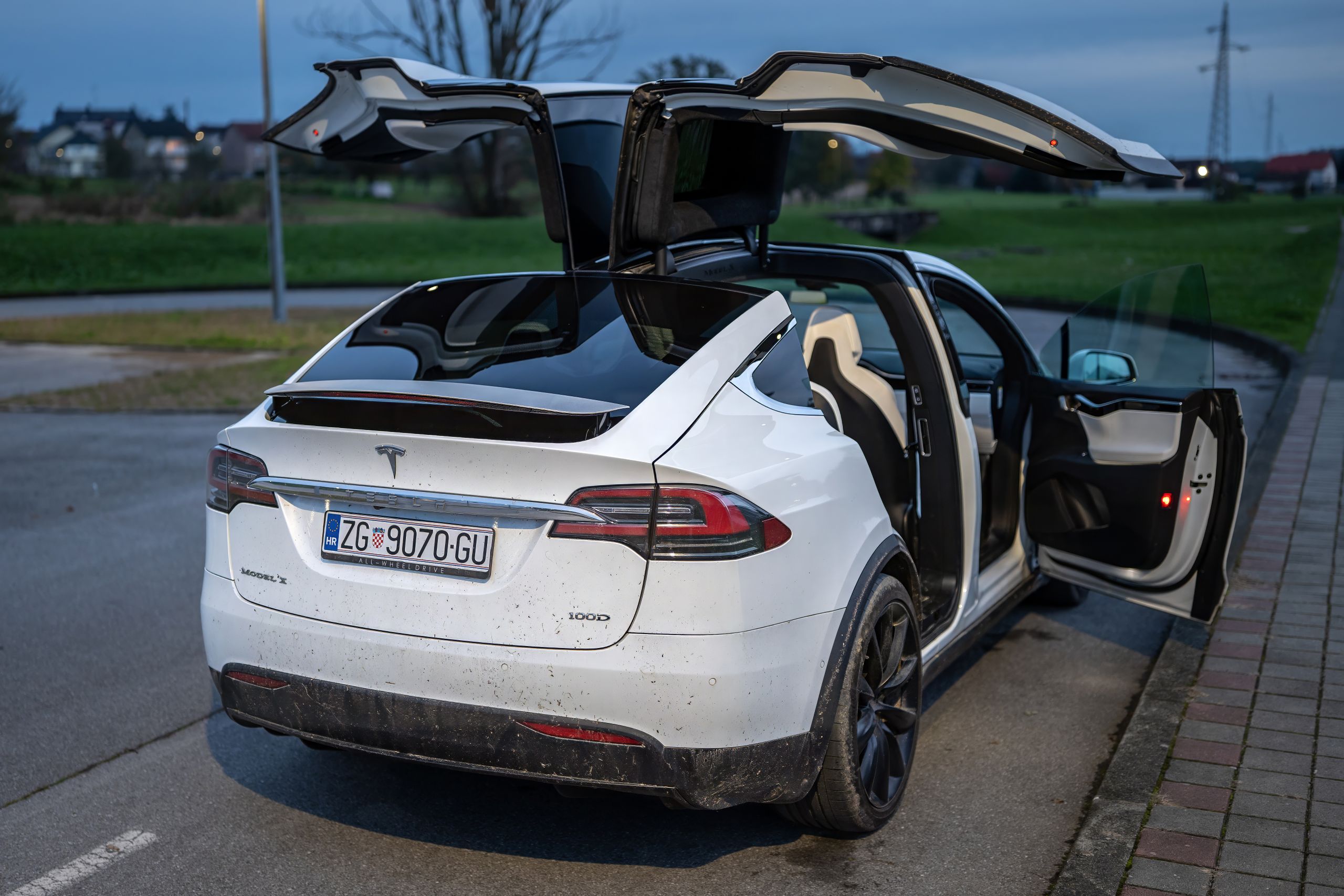 Stylish white electric car with open doors parked on an urban road, showcasing modern design.