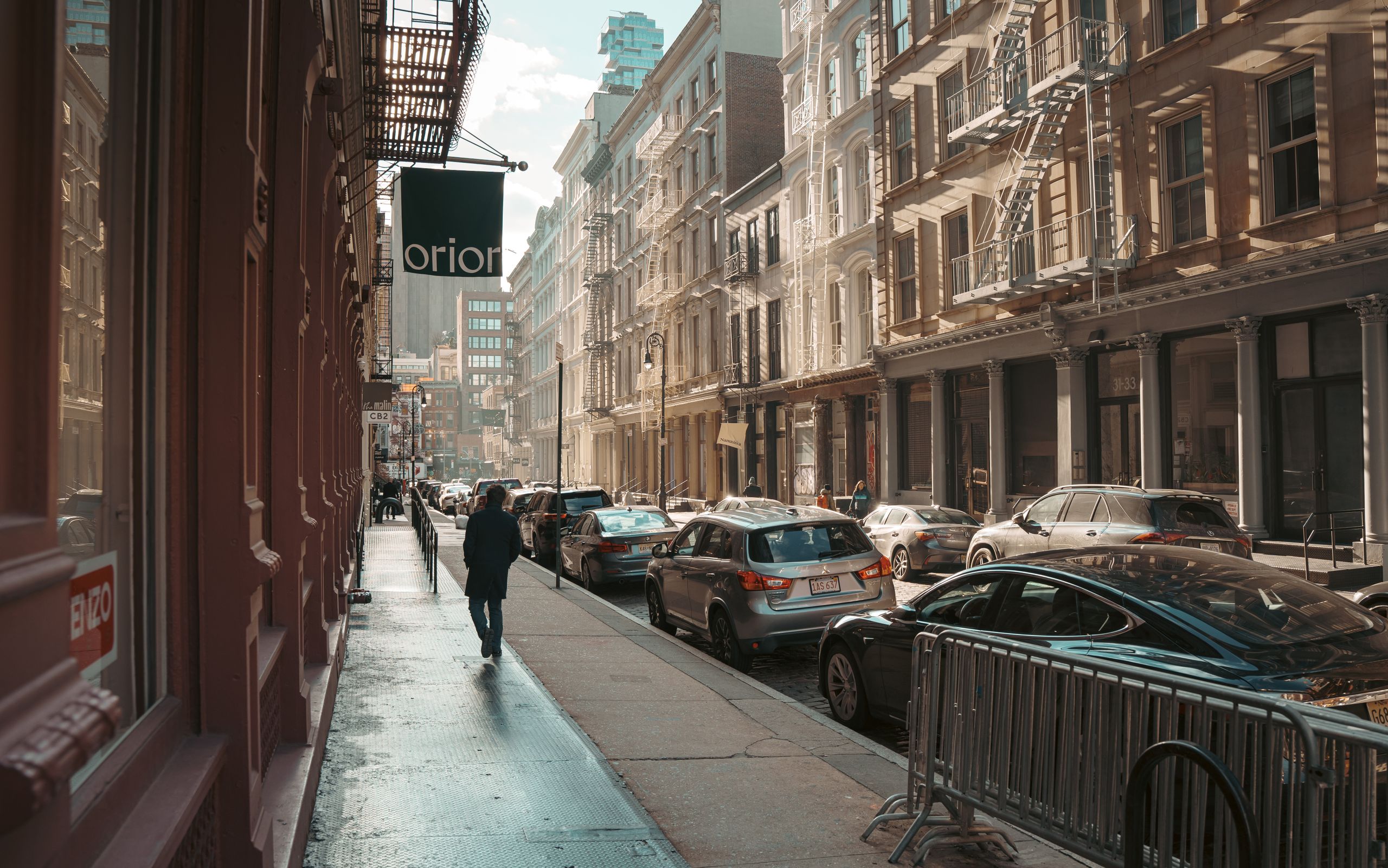 Sunlit street in Manhattan with cars and buildings, capturing the essence of NYC architecture.