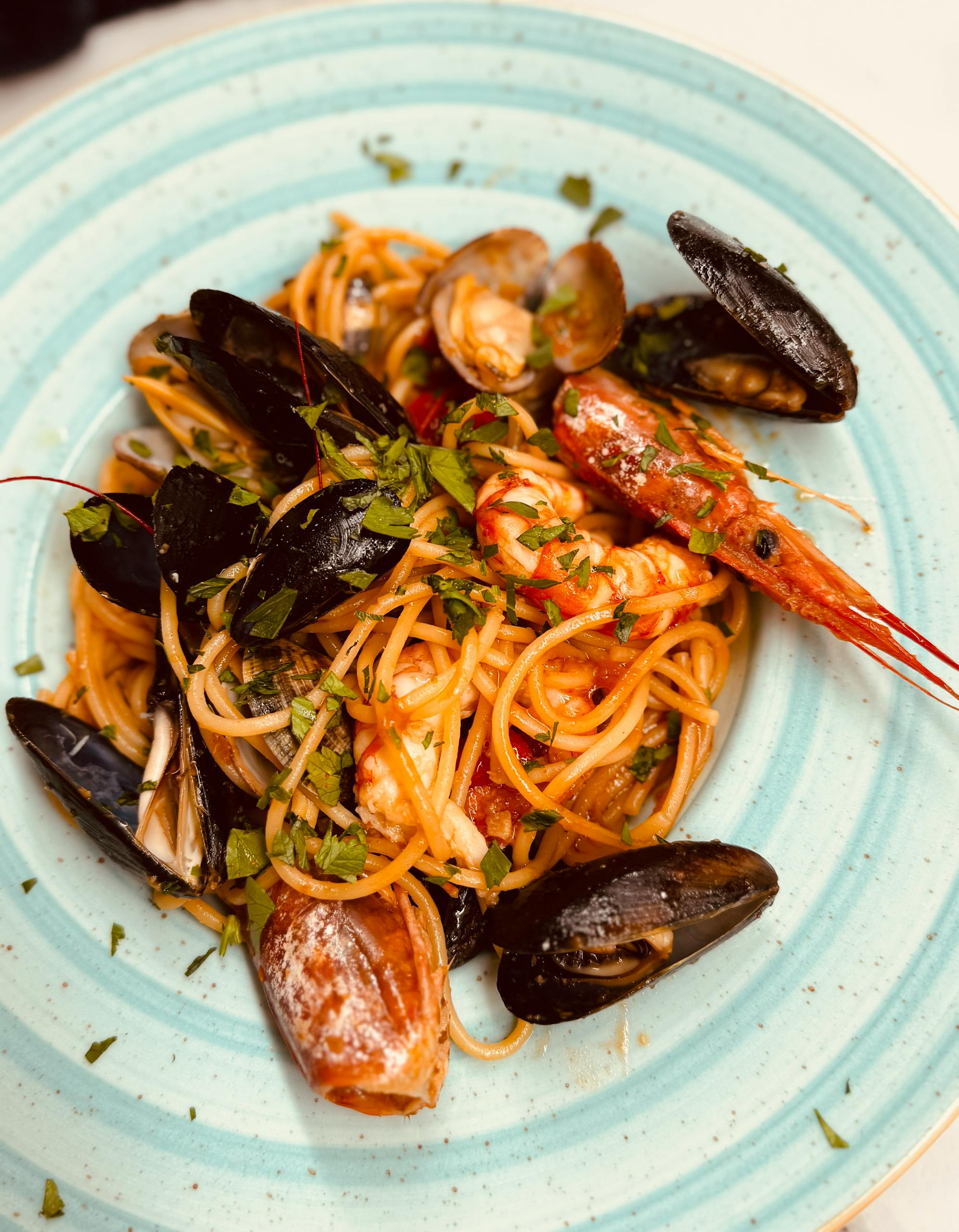 Tantalizing seafood spaghetti with mussels and shrimp, elegantly served on a white plate. Perfect for gourmet dining visuals.