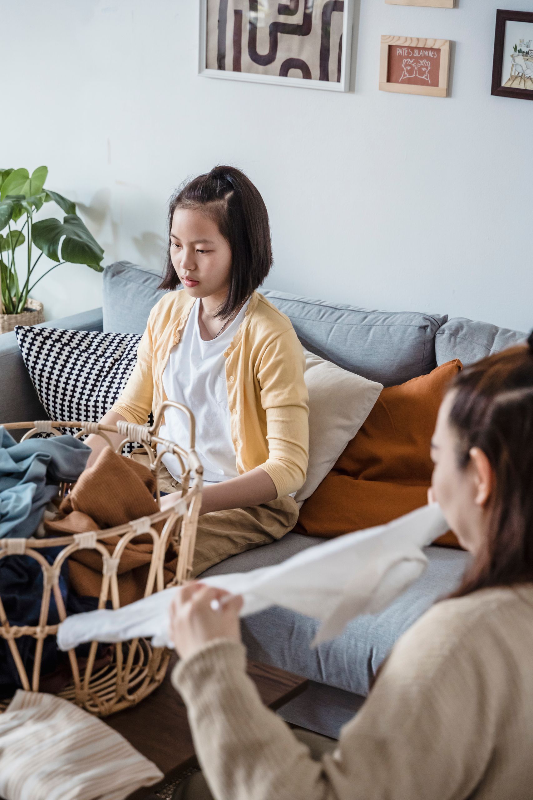 Teenager folding laundry with a family member in a cozy living room setting.