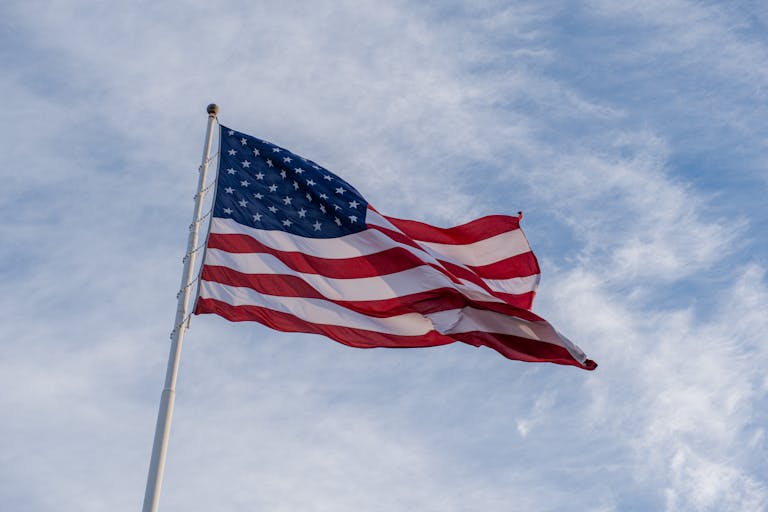 The American flag waves proudly against a backdrop of blue sky, symbolizing freedom and patriotism.