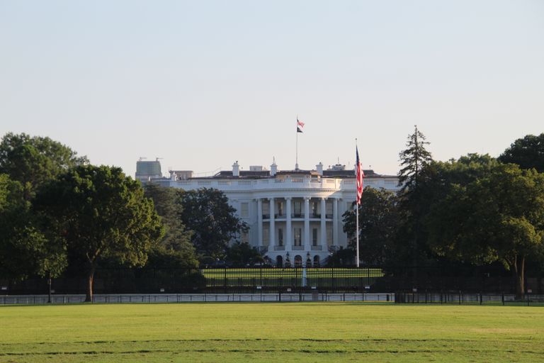 The White House surrounded by greenery under a clear sky.