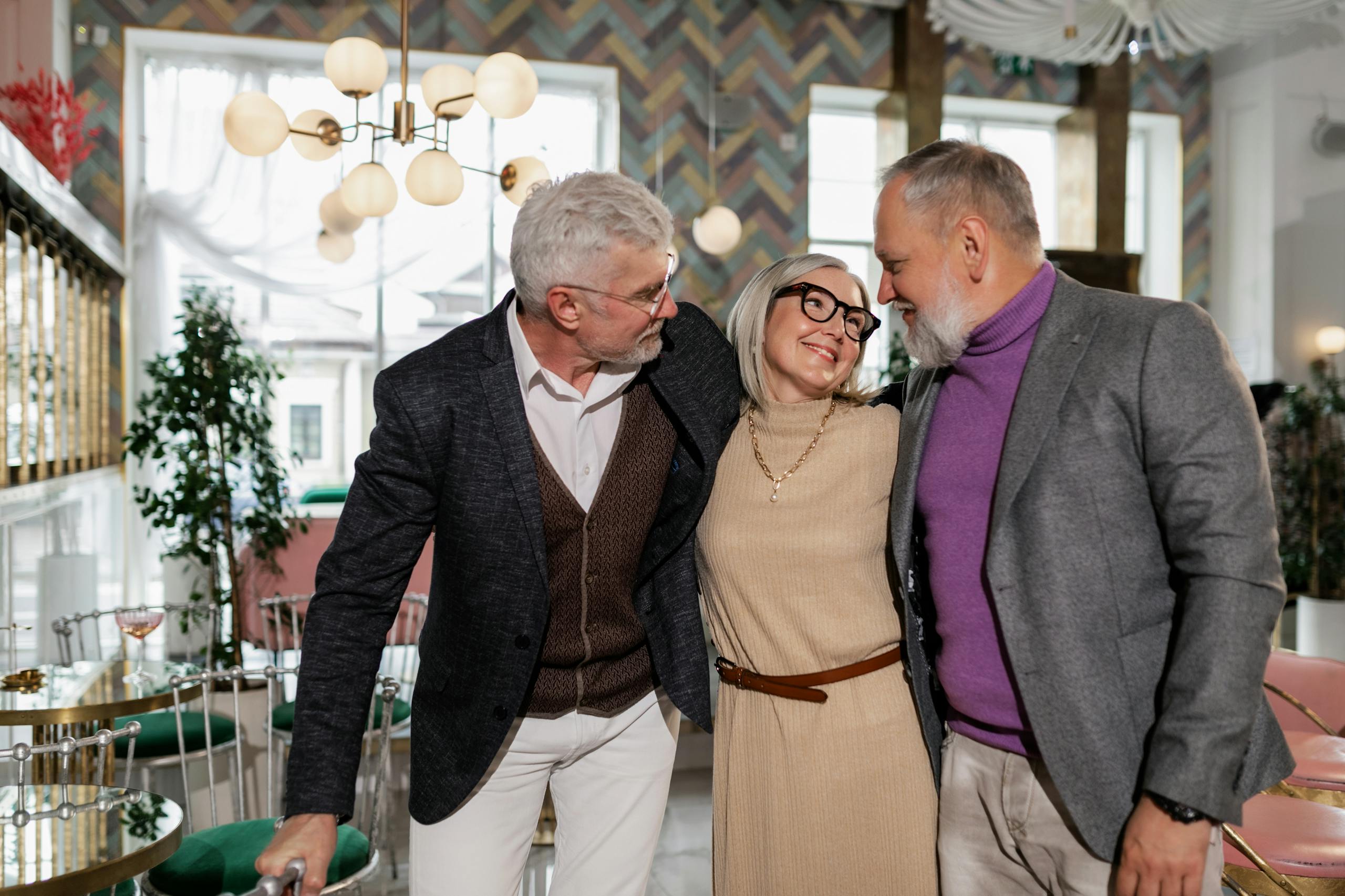 Three senior friends laughing and bonding in a stylish cafe setting.