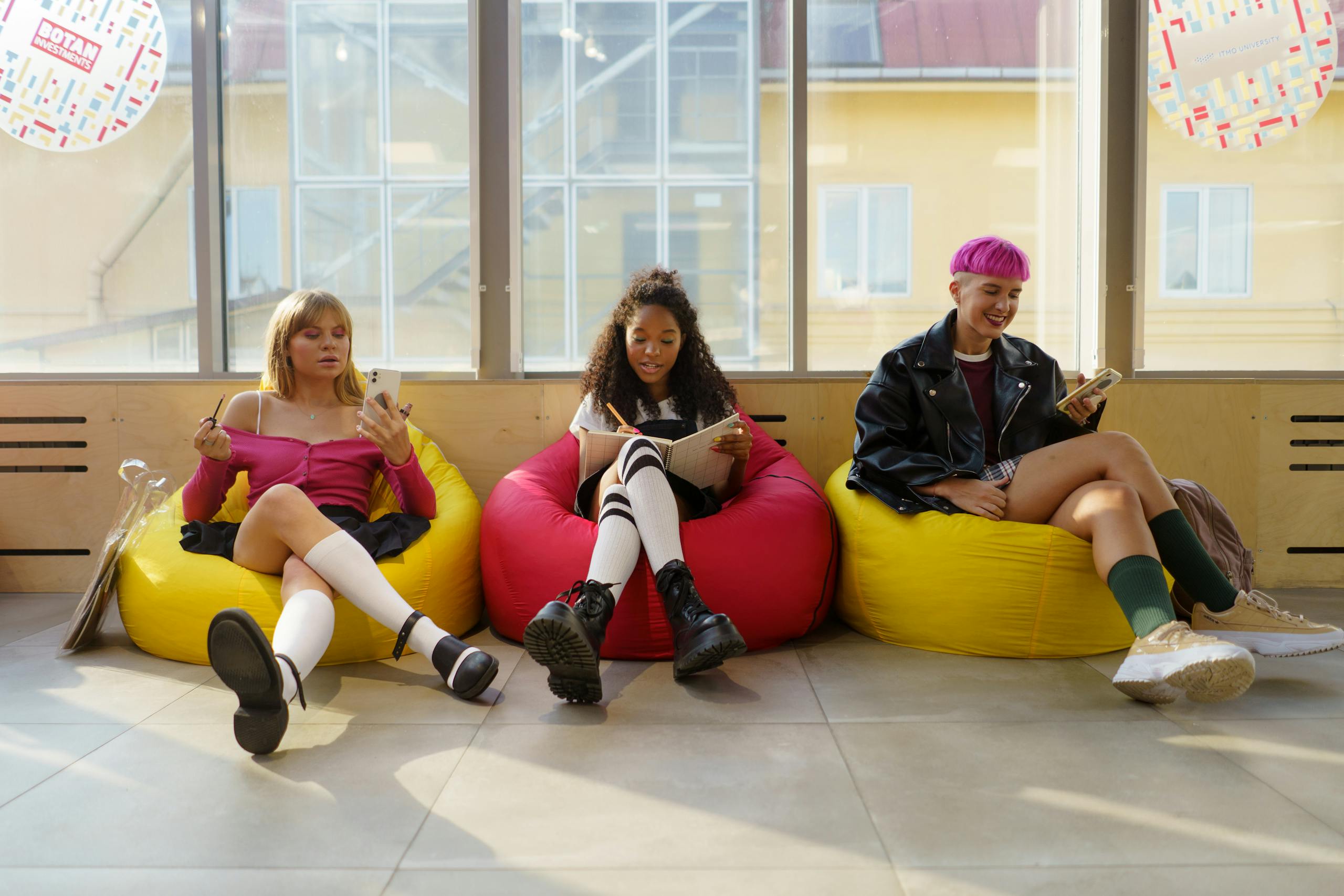 Three teenagers relaxing in colorful bean bags, enjoying leisure time indoors.