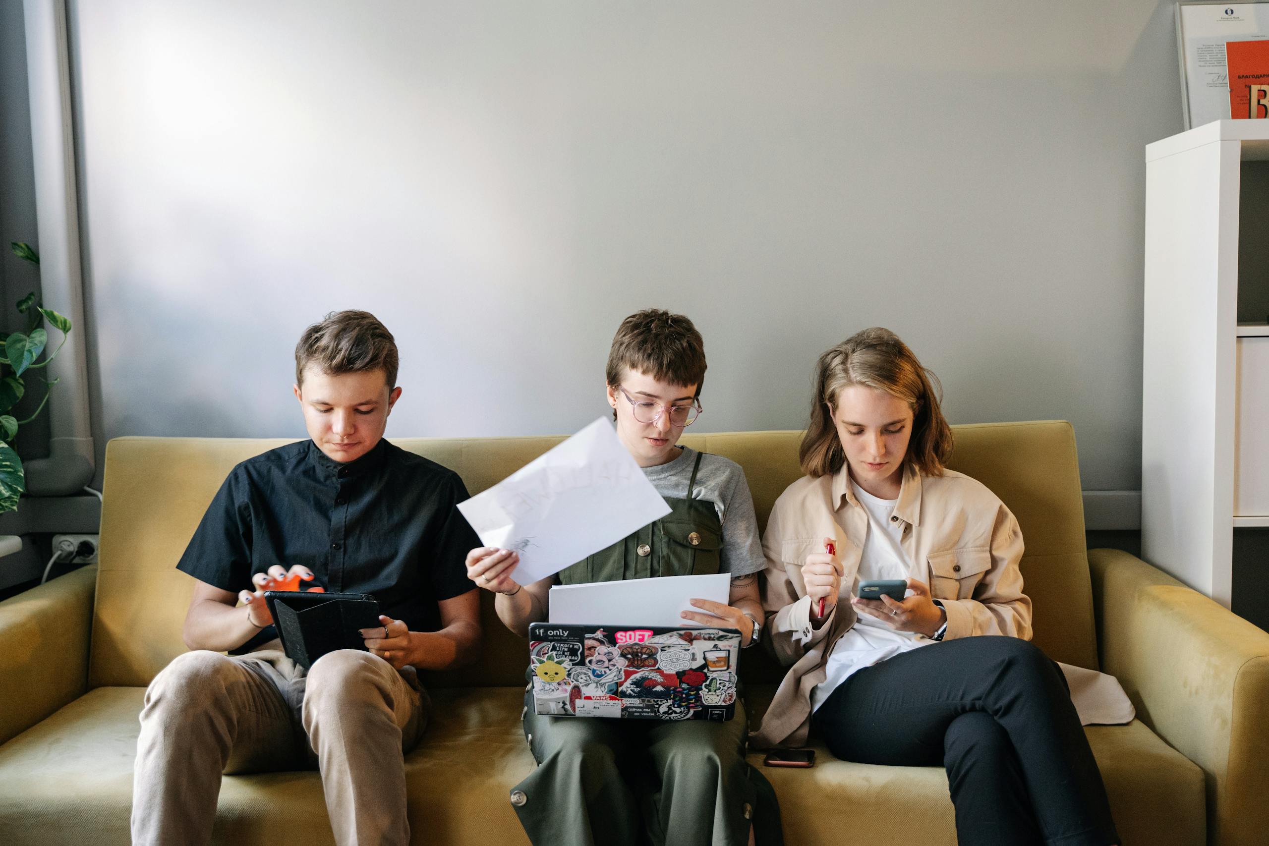 Three young adults concentrating on work in a collaborative office setting.