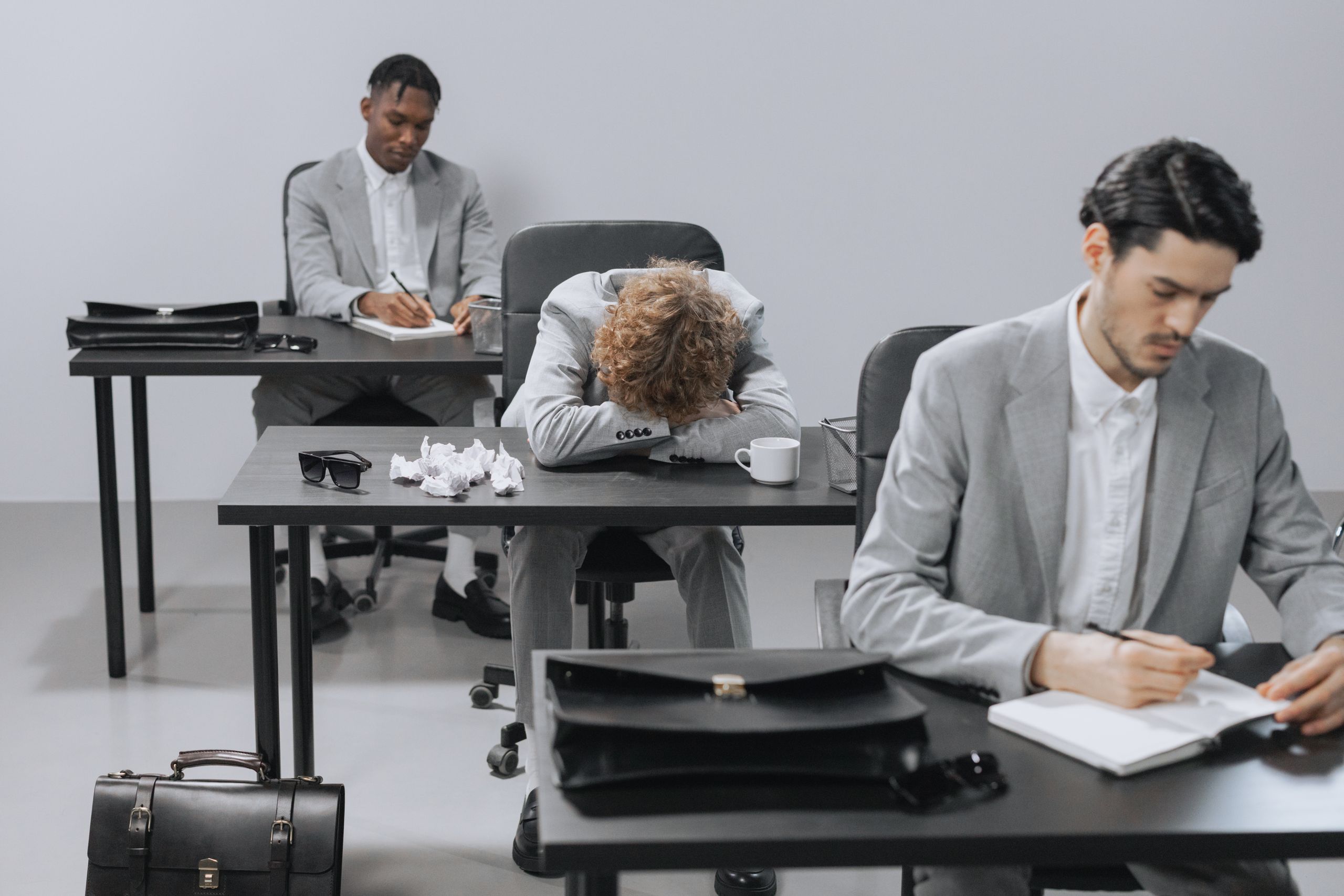 Tired employees in a modern office setting showing signs of workplace exhaustion.